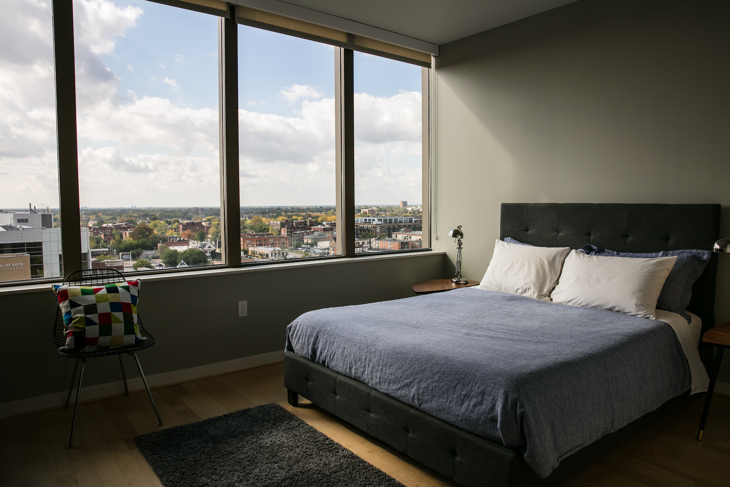 A bedroom with windows overlooking a city.