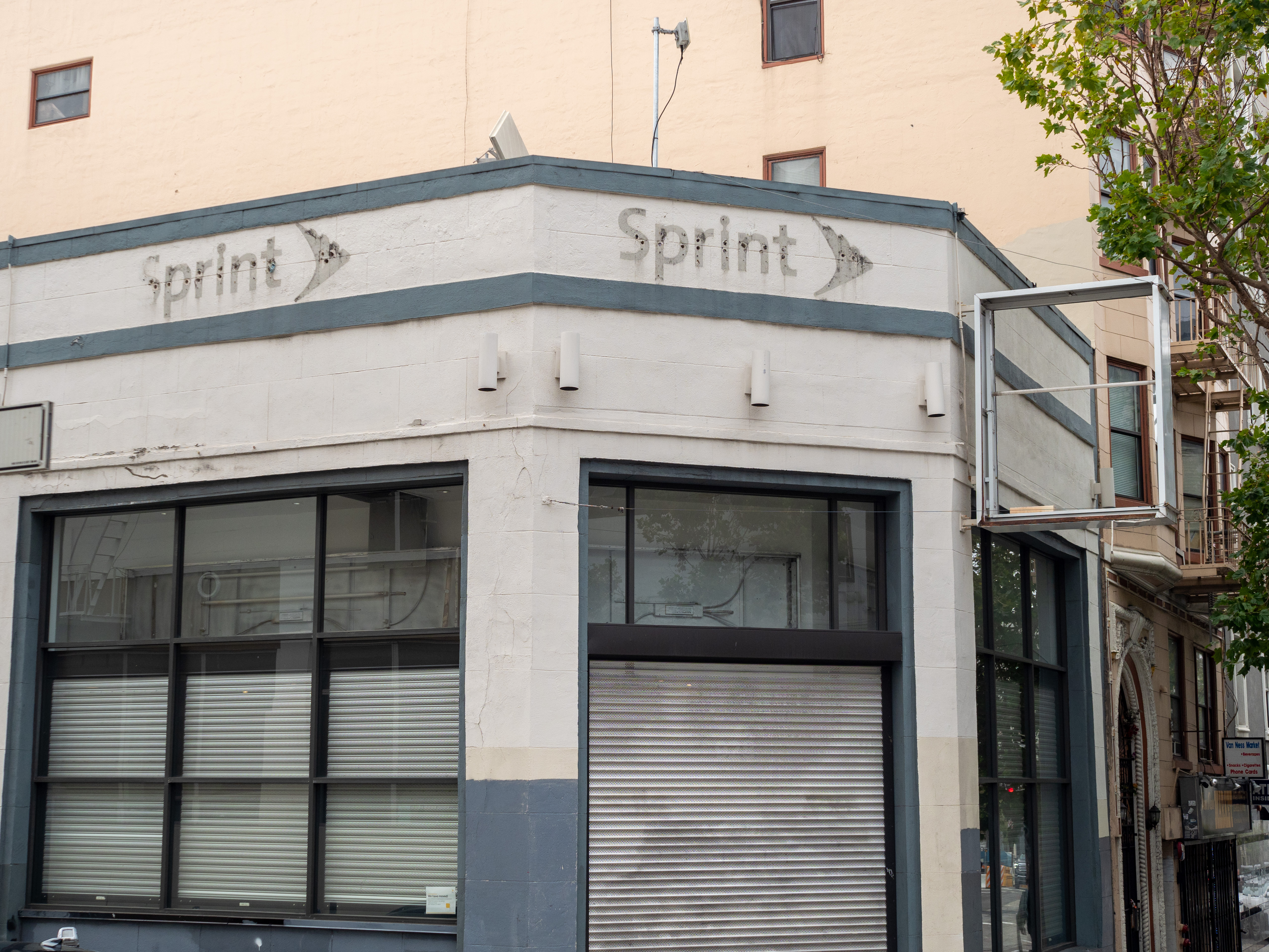 A closed up shop corner with shutters in the window closed and the outline of “sprint” on top.