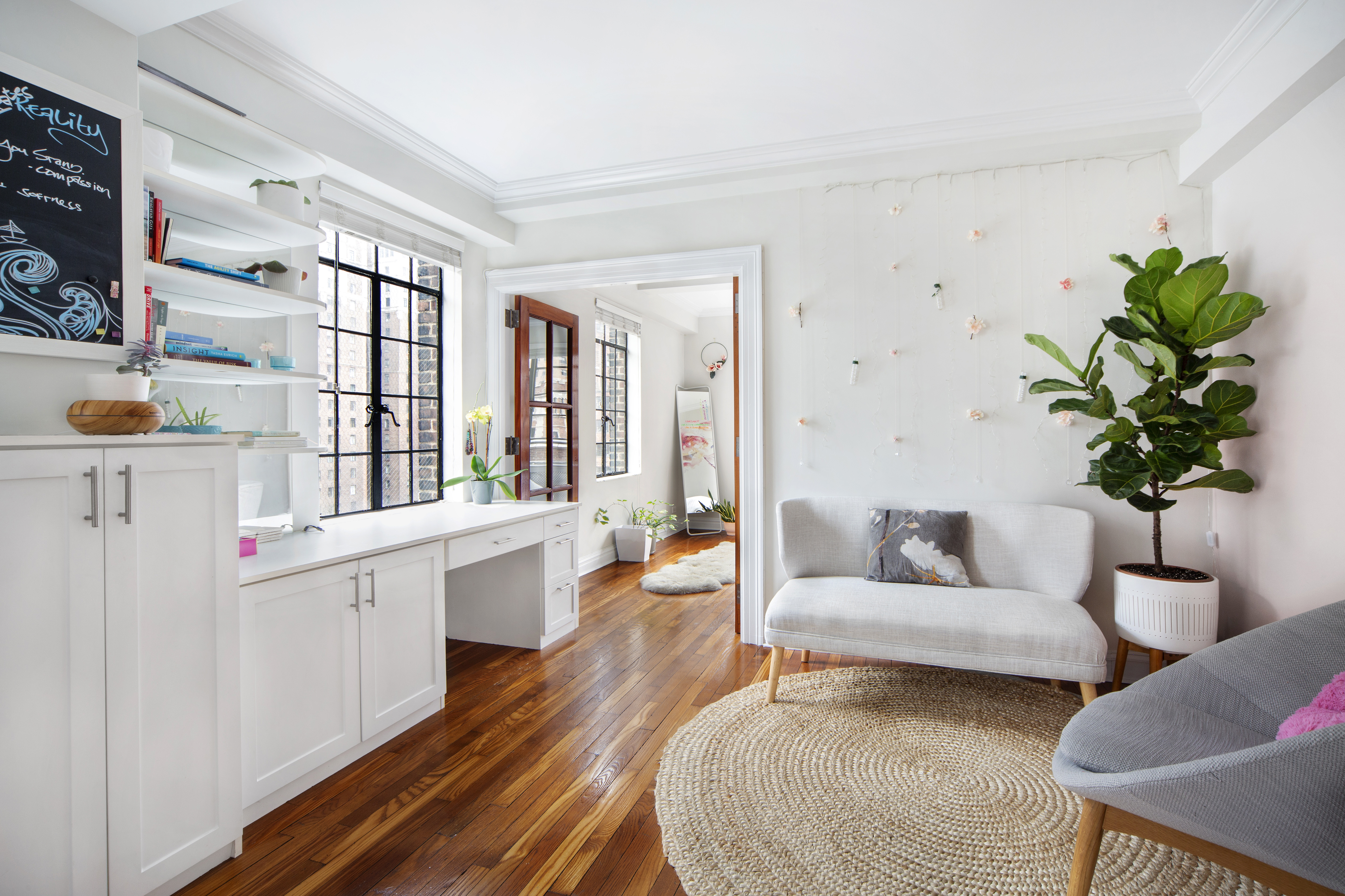 A white living area with casement windows and white built-in cabinets on the east wall.