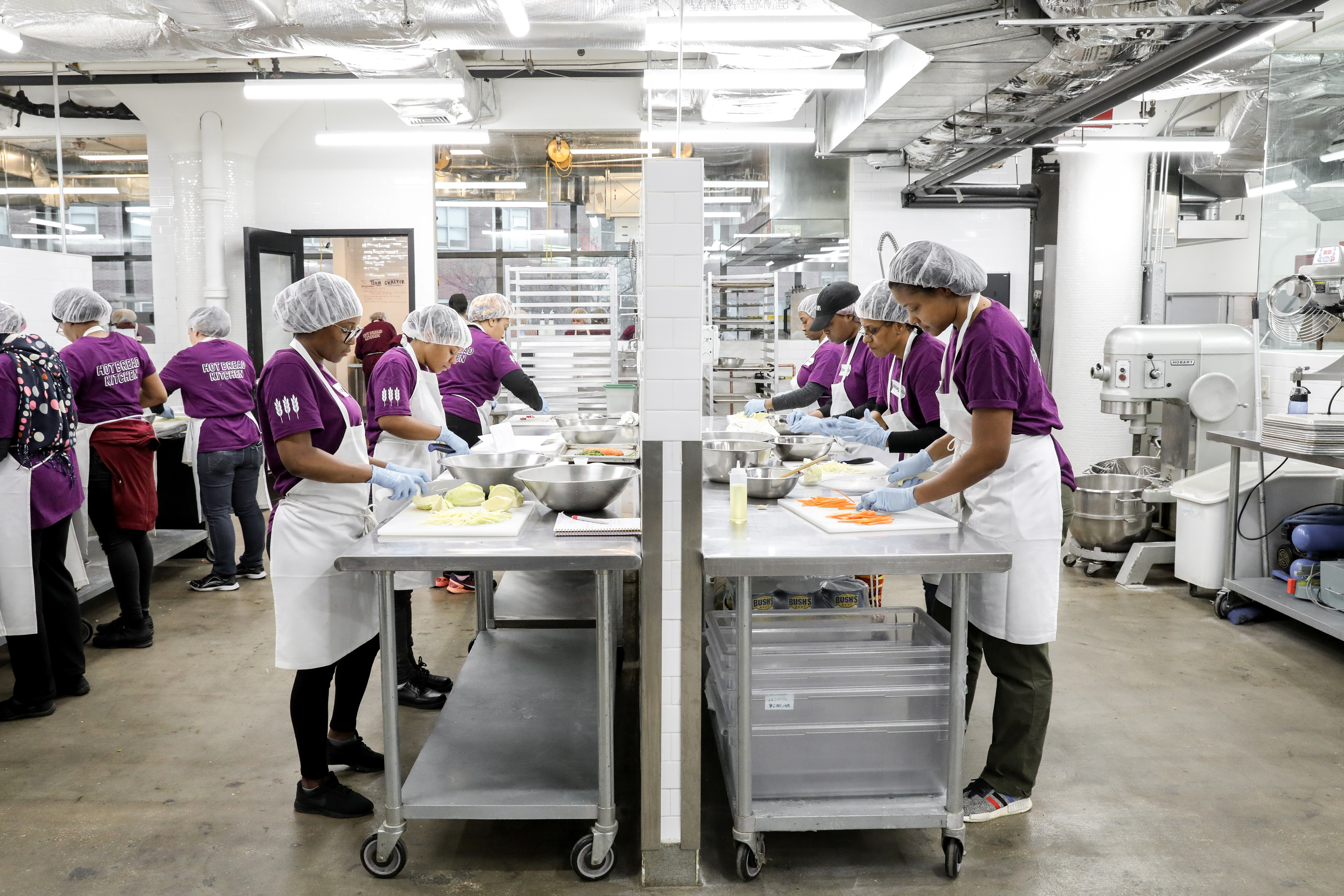 Culinary students wearing Hot Bread Kitchen shirts, standing at workstations at the non-profit’s new headquarters