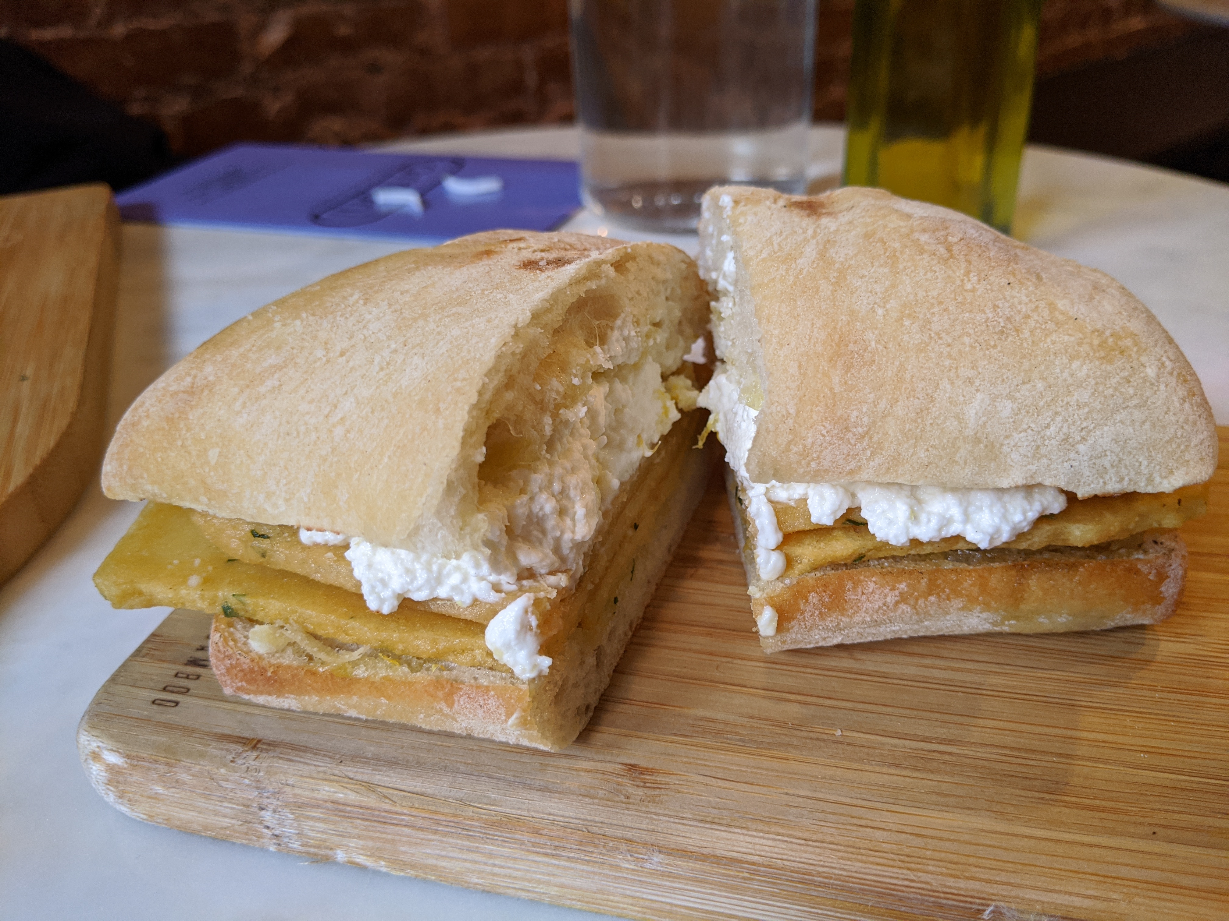 A sandwich of yellow slabs of fried chickpea paste and ricotta cheese.