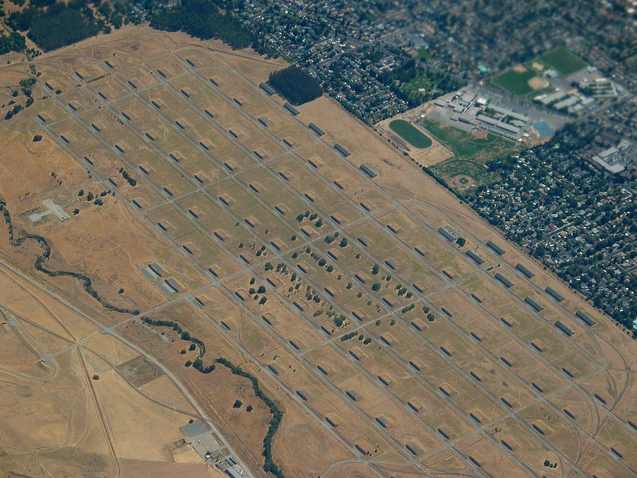An aerial photo of the Concord Navy base, with gray concrete structures dotting a plain of yellow grass.