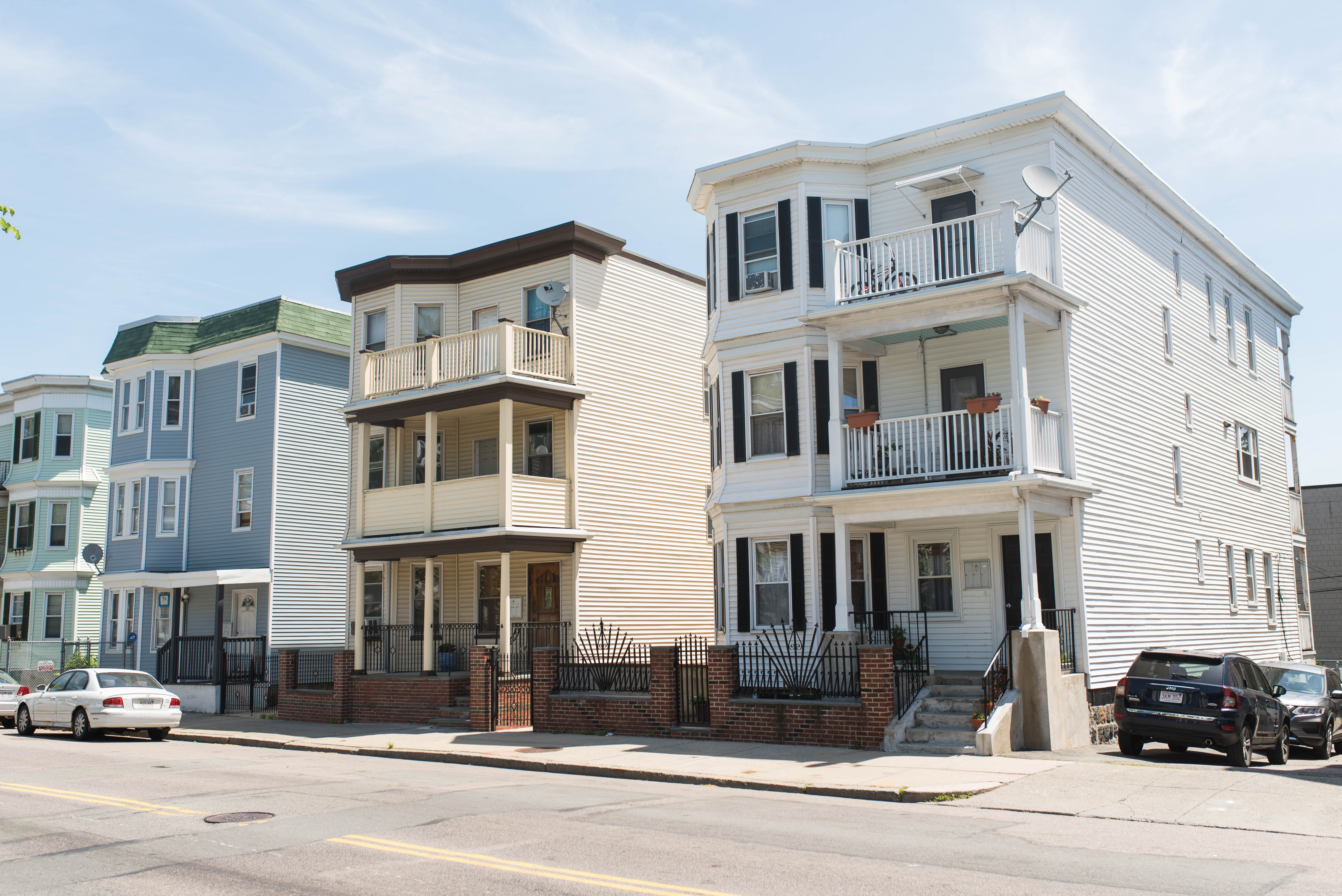 A row of three-story apartment houses on a sidewalk.