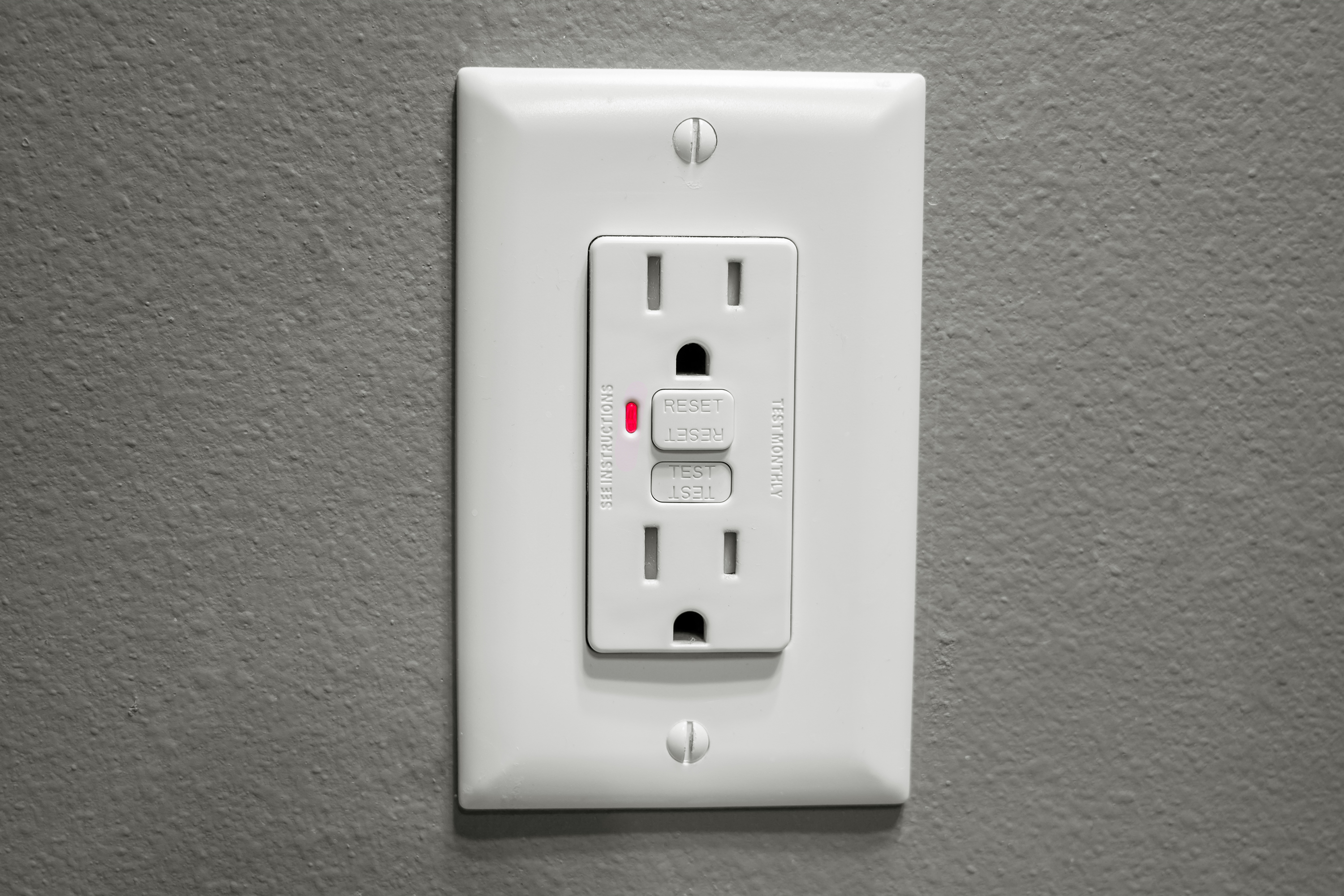 GFCI outlet on gray wall.