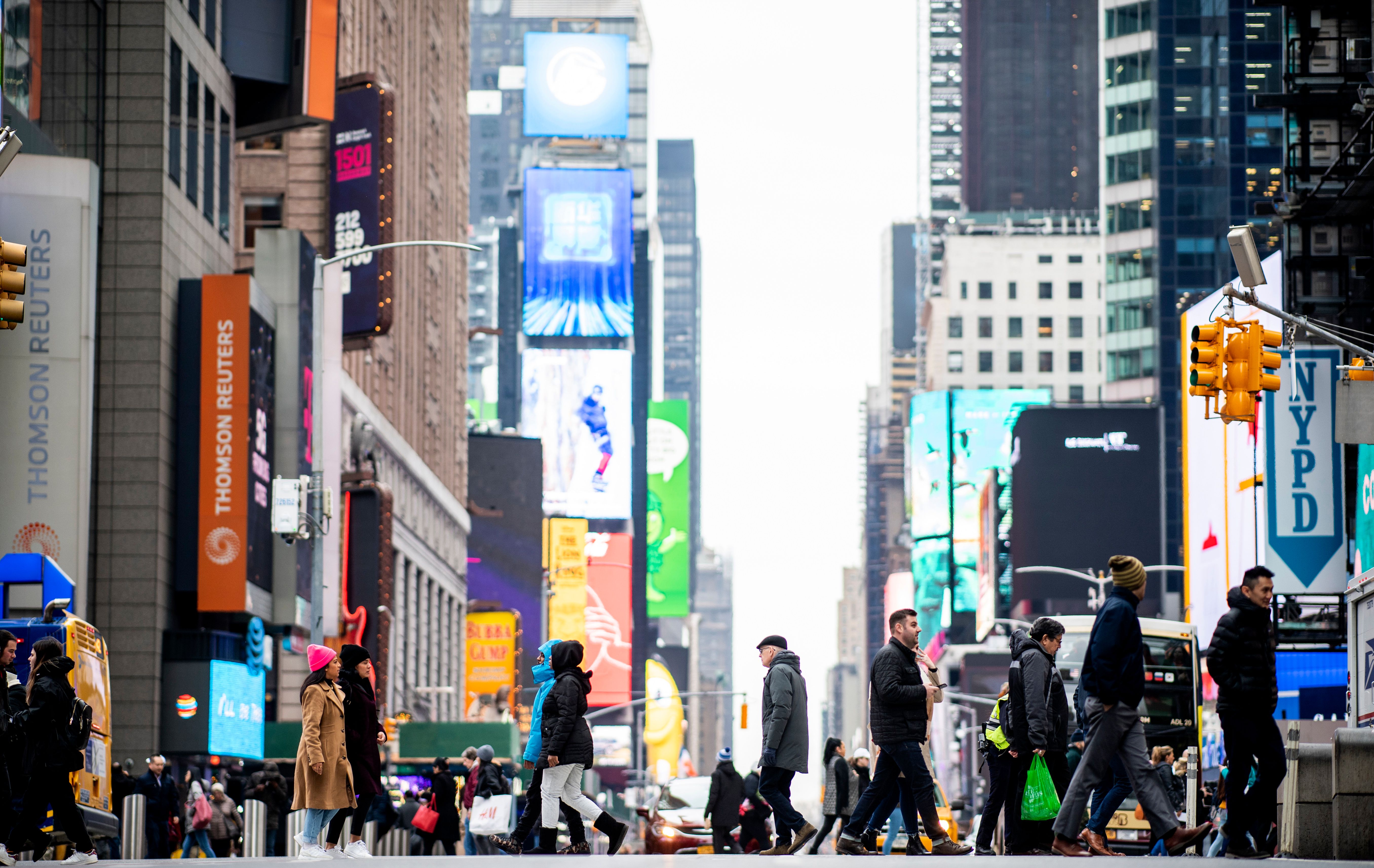 A crowd of people walking across 42nd Street in Times Square on January 14, 2020