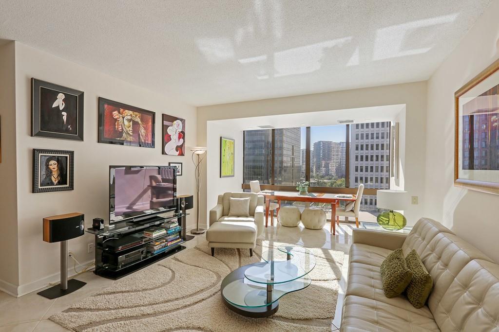 A white condo with a white couch at right and skyline views out the window.