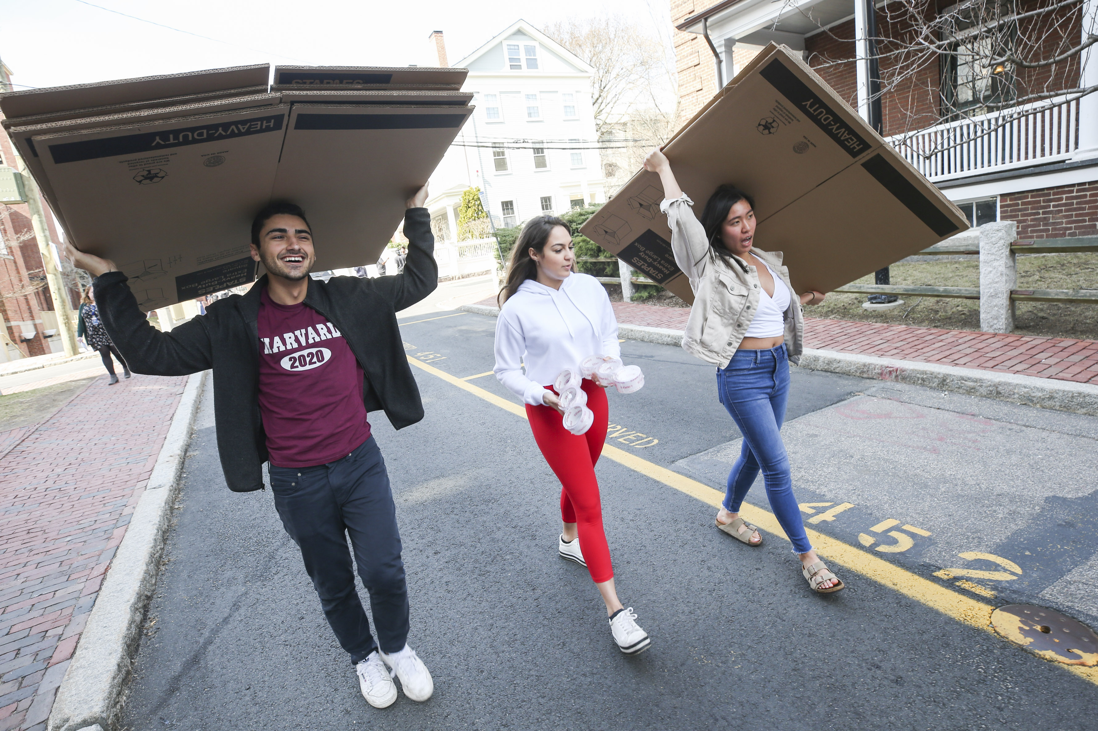 在哈佛大学，三个大学生拿着纸板箱，准备打包他们的物品搬出宿舍。