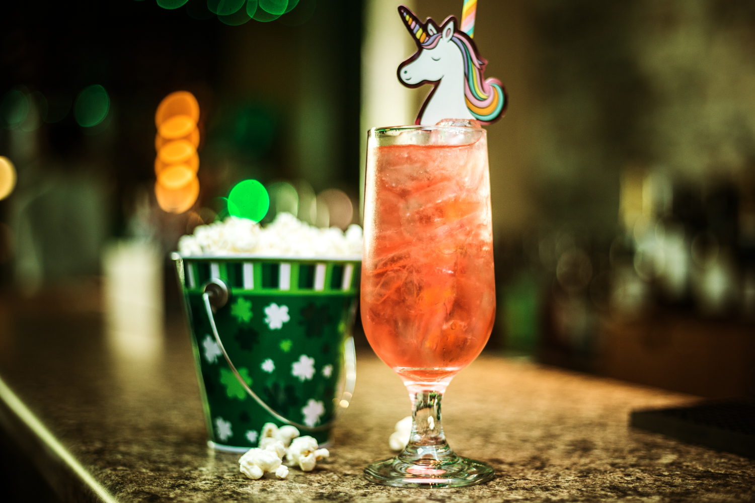 orange cocktail with unicorn straw and green bucket of popcorn with irish theme