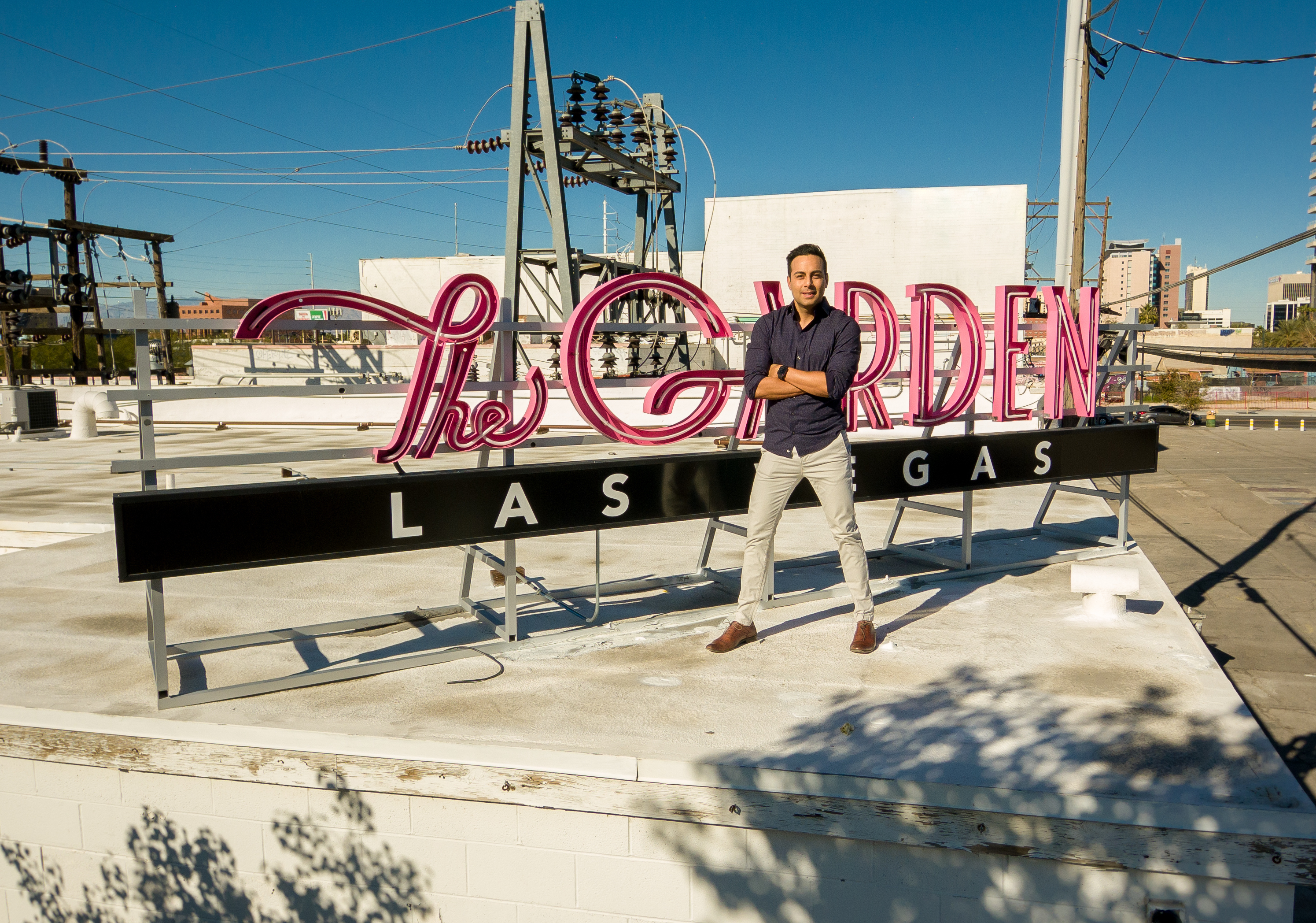 A man stands in front of a rooftop sign