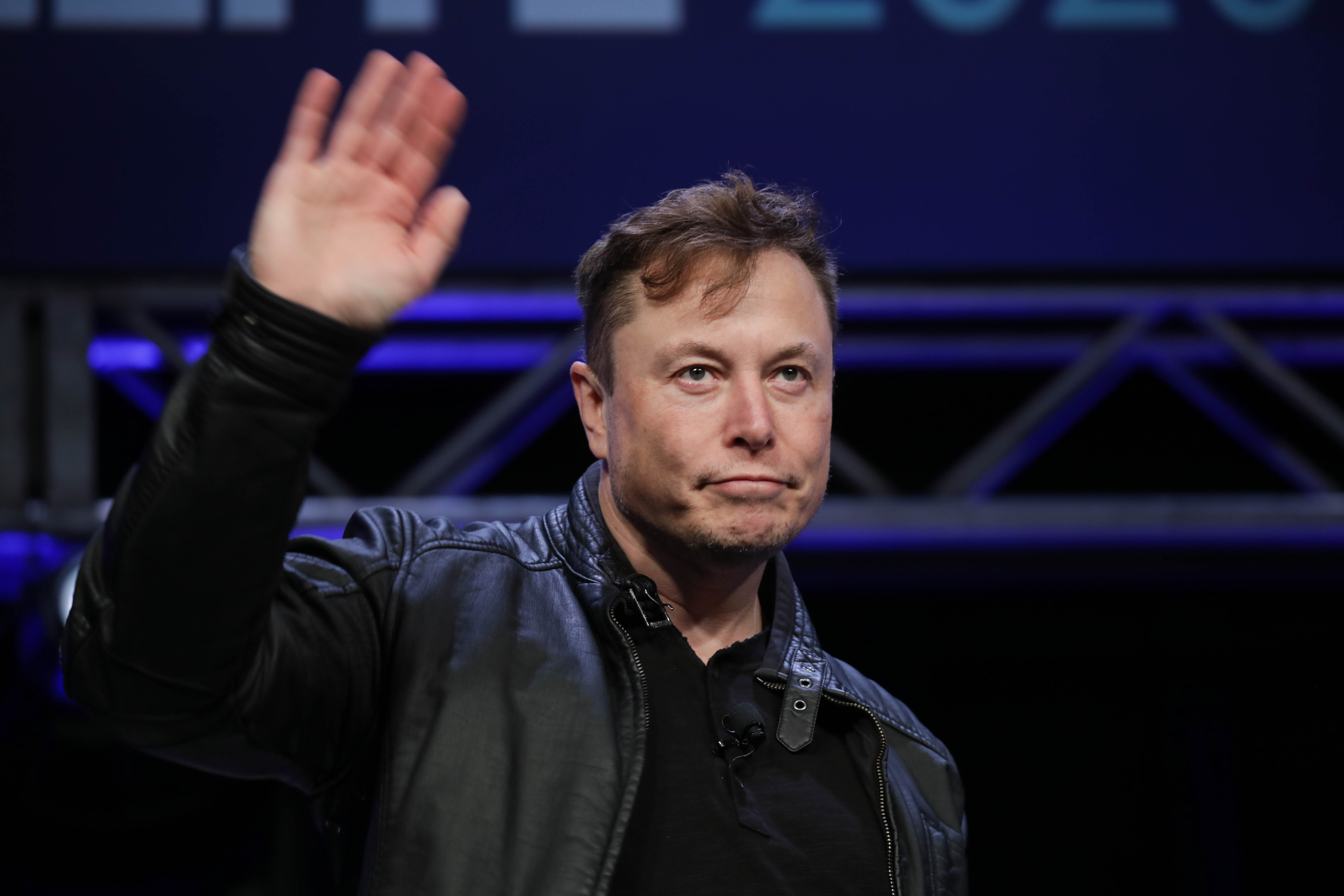 Elon Musk waves from a stage.