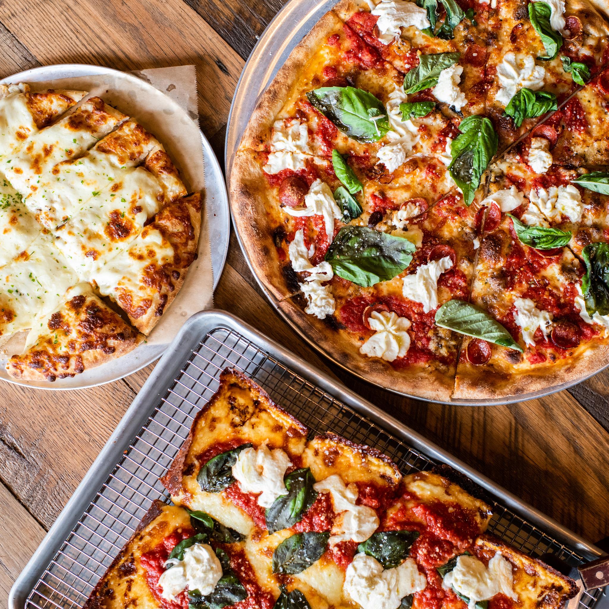 A plate of cheesy bread, a margherita pizza, and a Detroit-Style margherita pizza