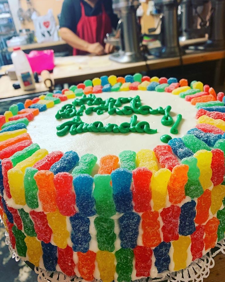 A white cake with a birthday inscription covered with gummy bears.