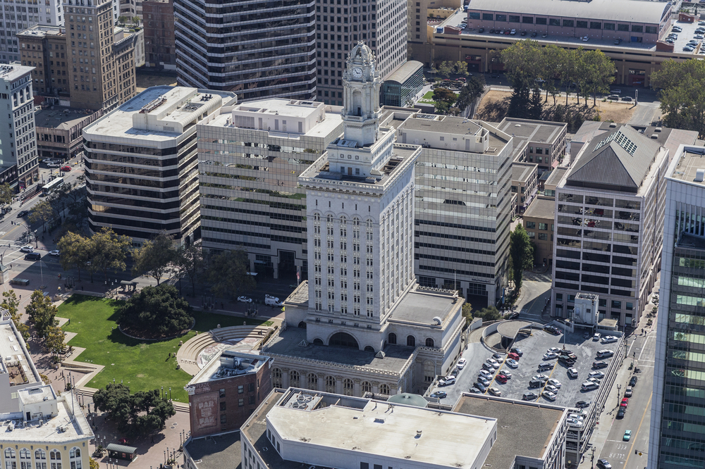 Afternoon aerial view of Oakland city hall, a tall white building with a spire.