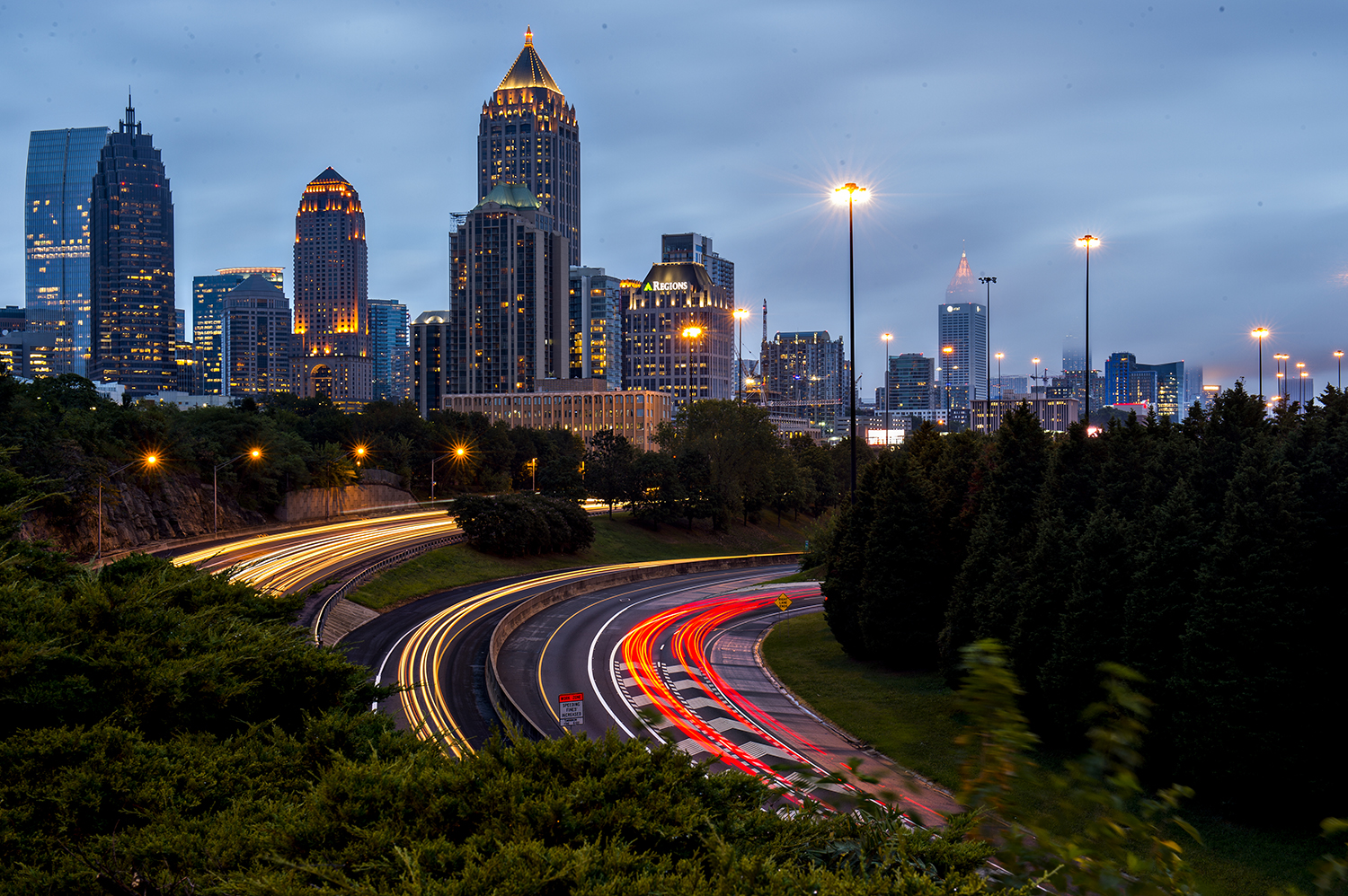 A scene of blurred traffic and many high-rises against a blue sky in Atlanta.