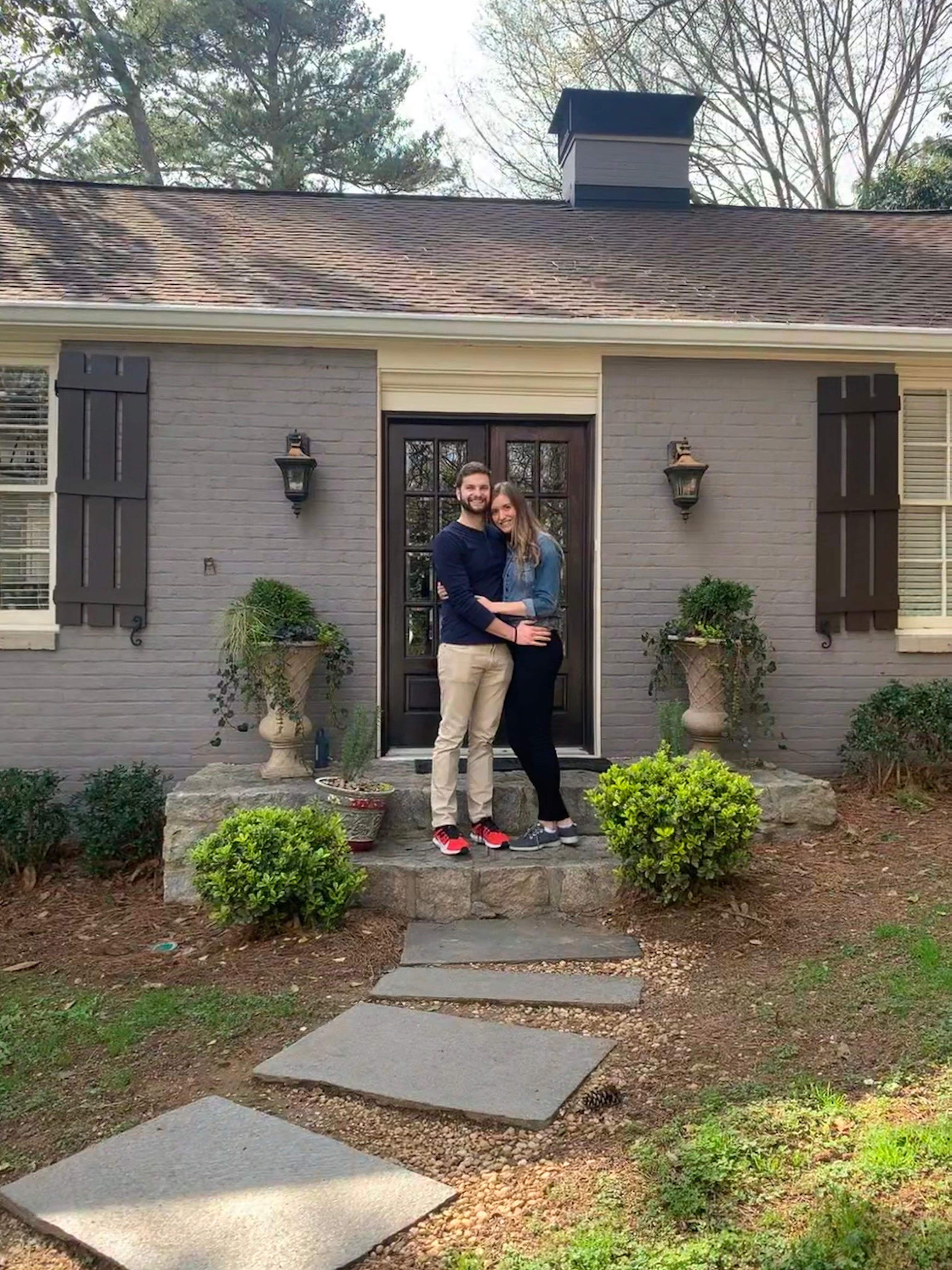 A couple stands in front of their new home in Atlanta’s Tuxedo Park neighborhood. 