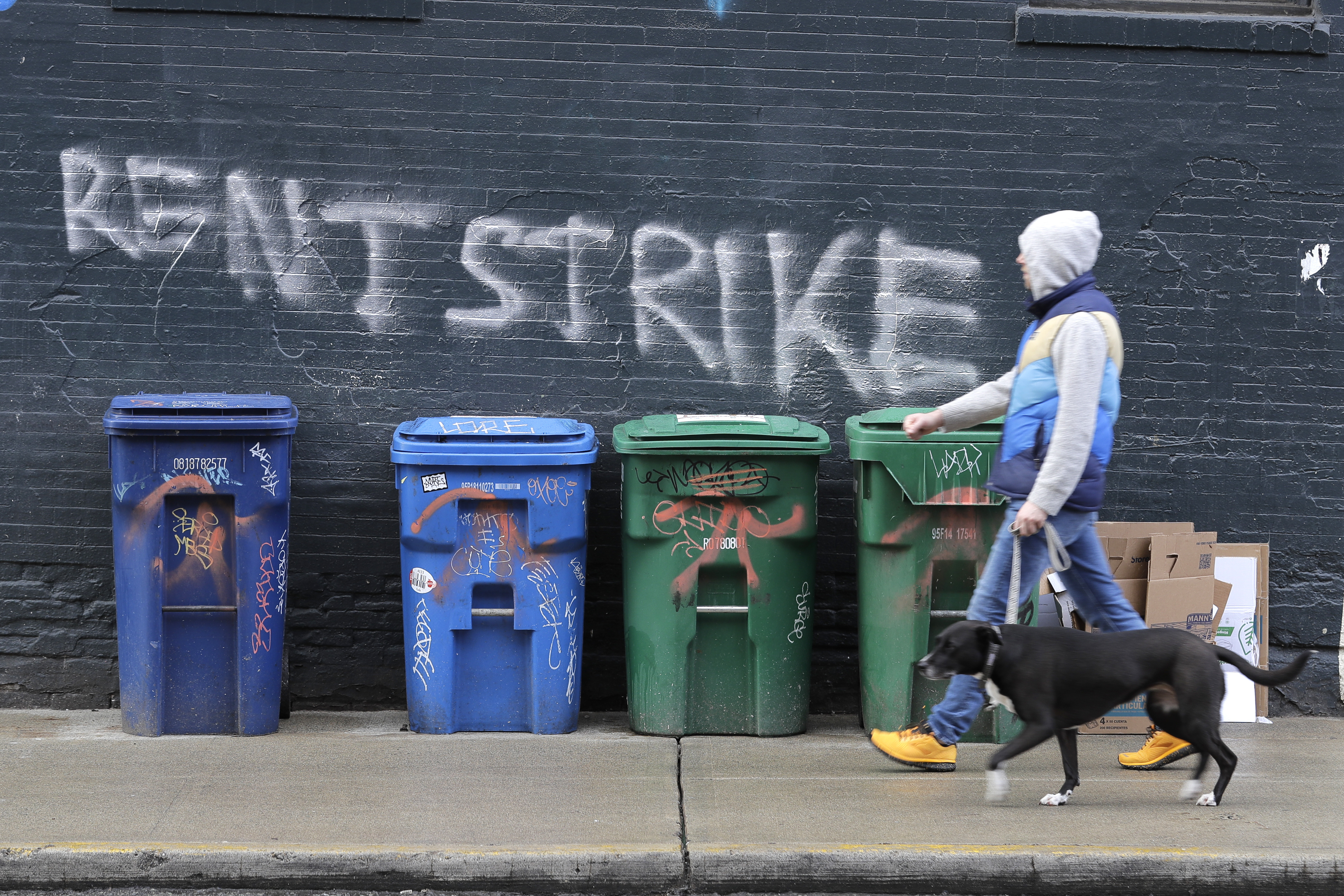 A pedestrian walks past graffiti that reads “Rent Strike.”