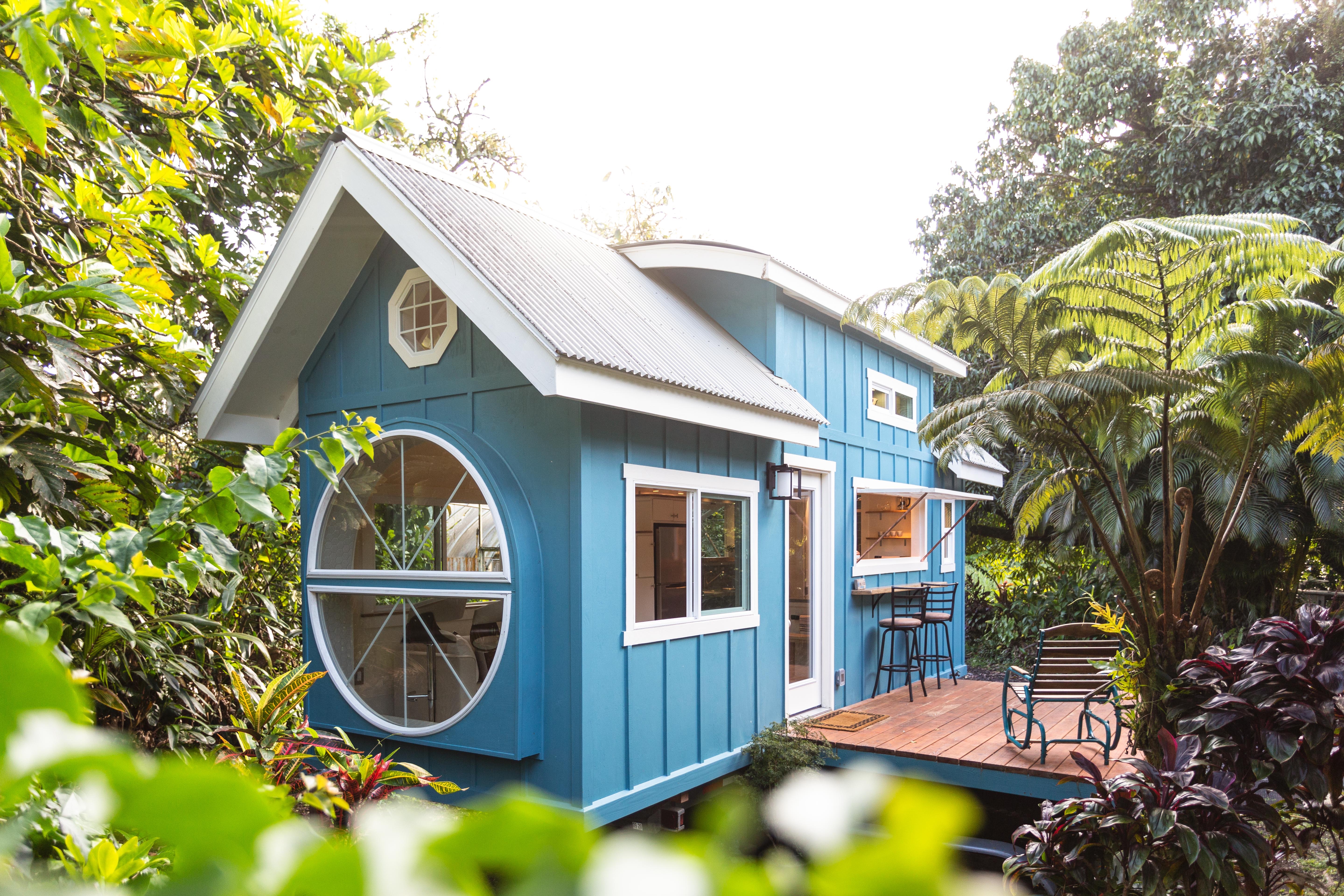 Blue tiny house with round windows at one end.