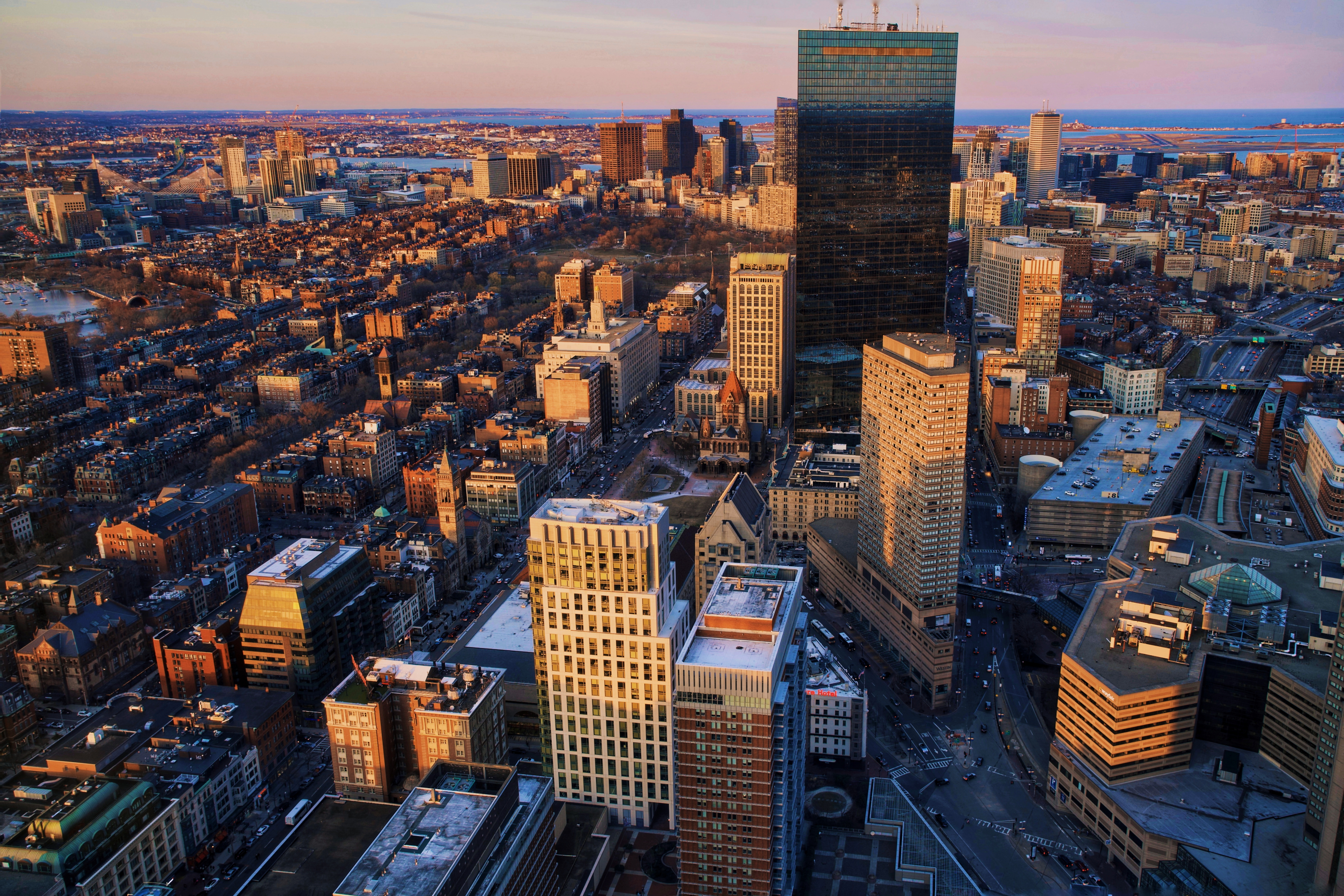 An aerial shot of the Boston skyline and the region beyond at sunset.