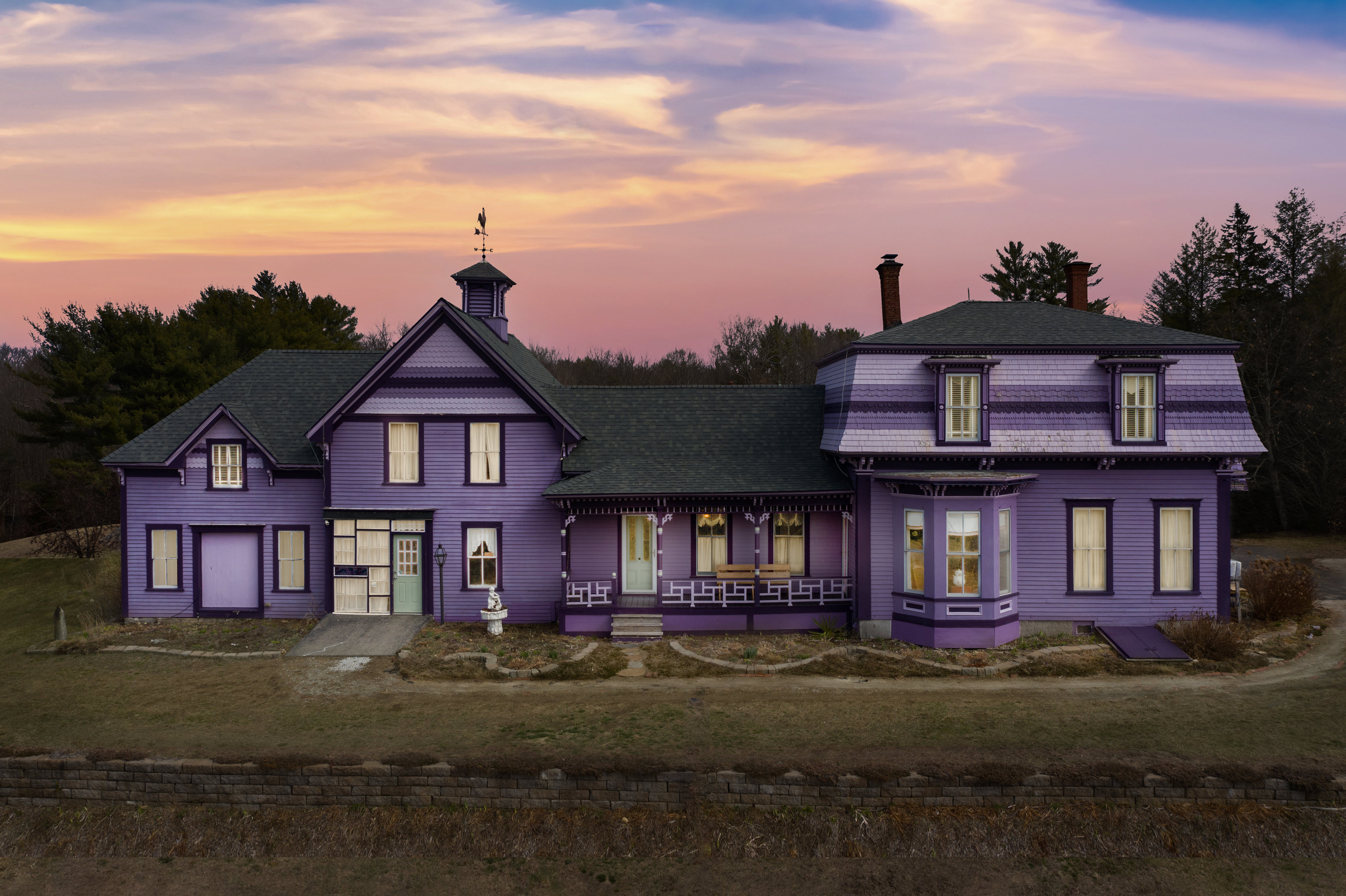 An exterior view of a Victorian house painted in many shades of purple. 