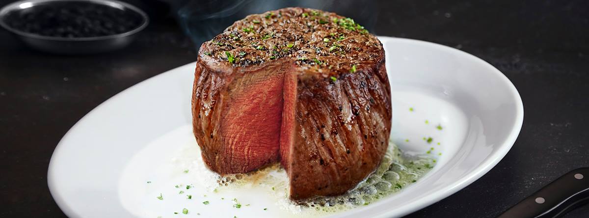 A steak filet that’s been cut into on a white plate.
