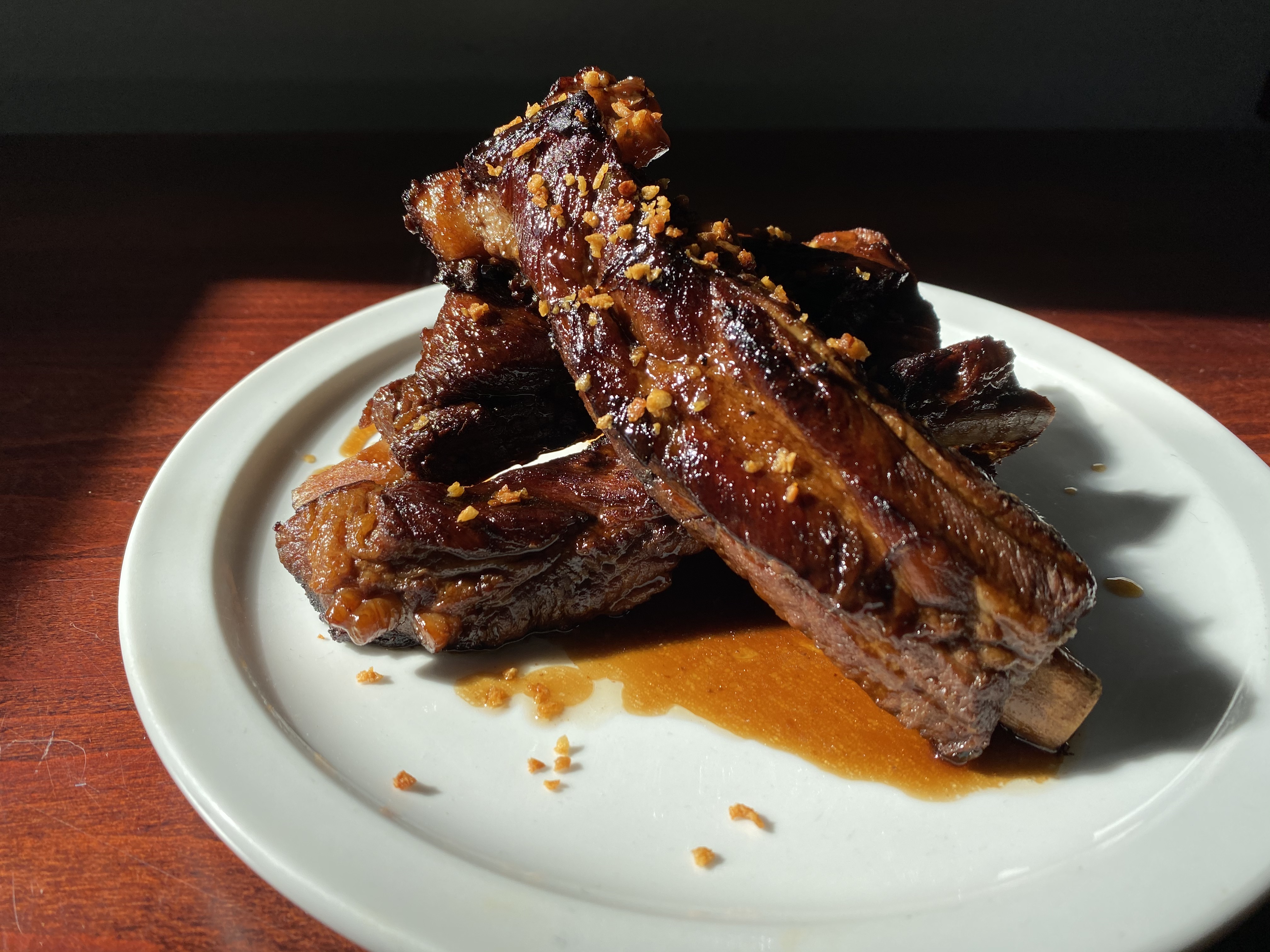 A closeup of adobong ribs na baboy from Musang on a white plate