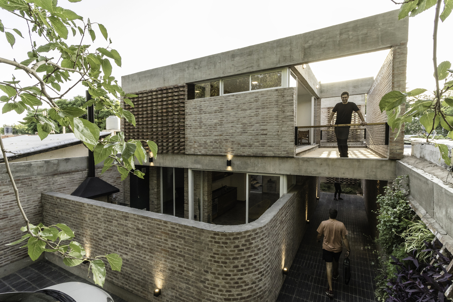 Man standing on terrace of brick clad building.