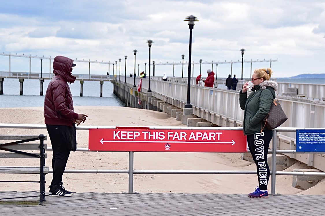 People talk to each other on the Coney Island Boardwalk in April while following social distancing guidelines. 