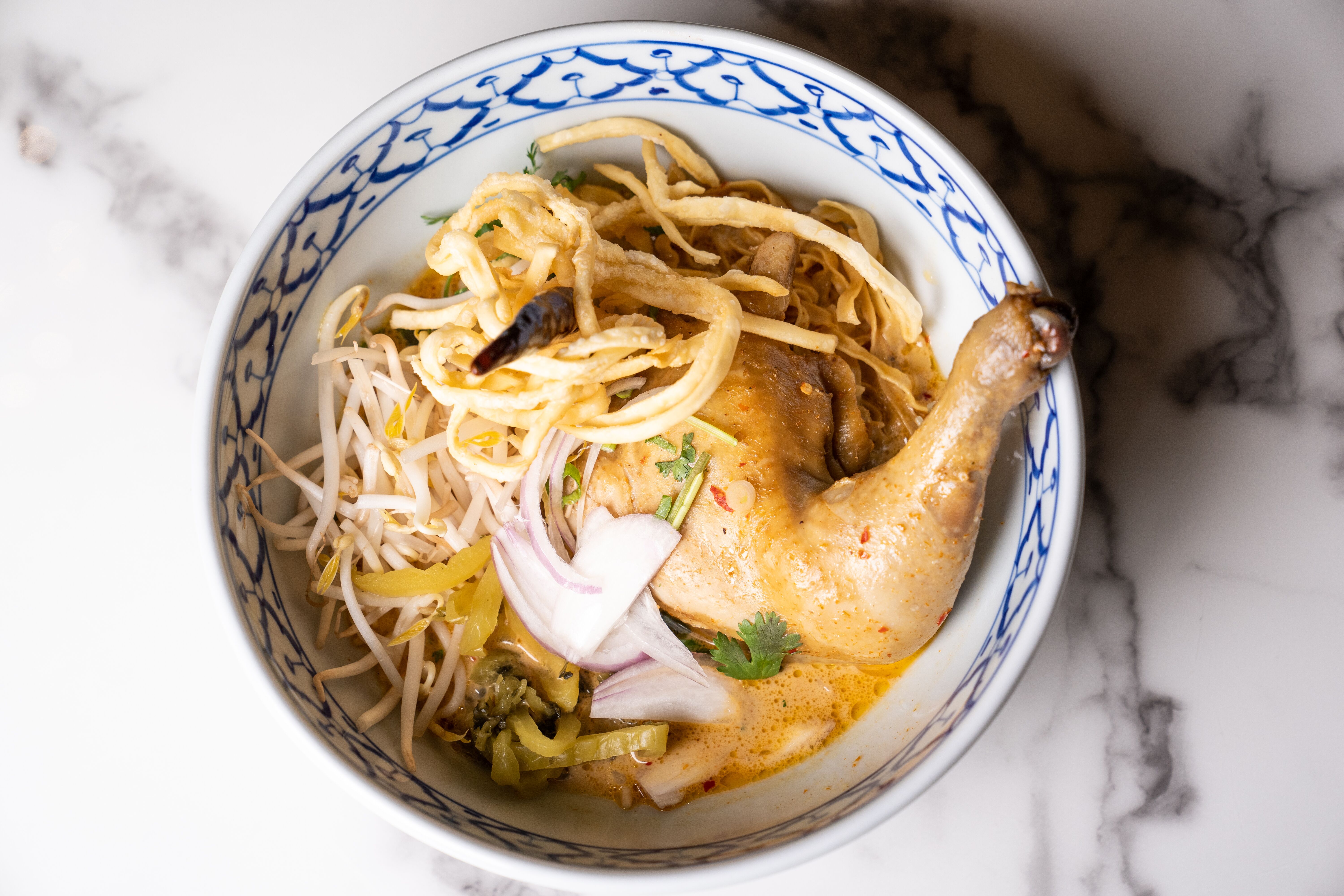 a cooked chicken thigh on a bed of thai curry noodles