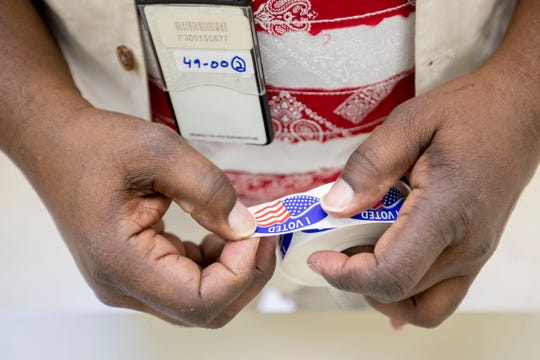 Poll worker Wardell Chambers tears stickers Tuesday, March 3, 2020, while voting at Pine Hills Community Center in Memphis.

