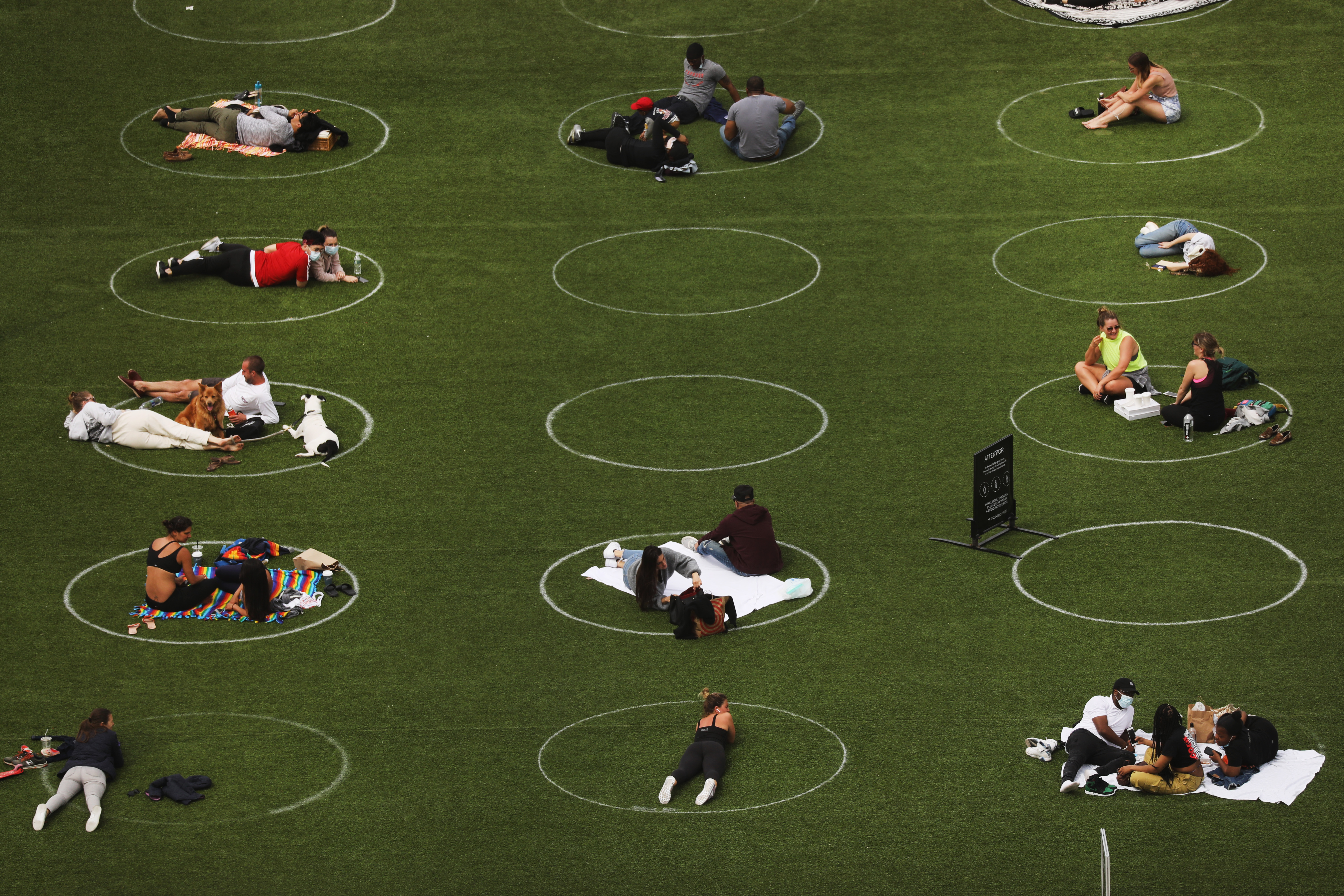 People sit in circles meant to encourage social distancing during the coronavirus pandemic in Domino Park along the East River on May 18, 2020 in the Williamsburg neighborhood of the Brooklyn borough in New York City. 