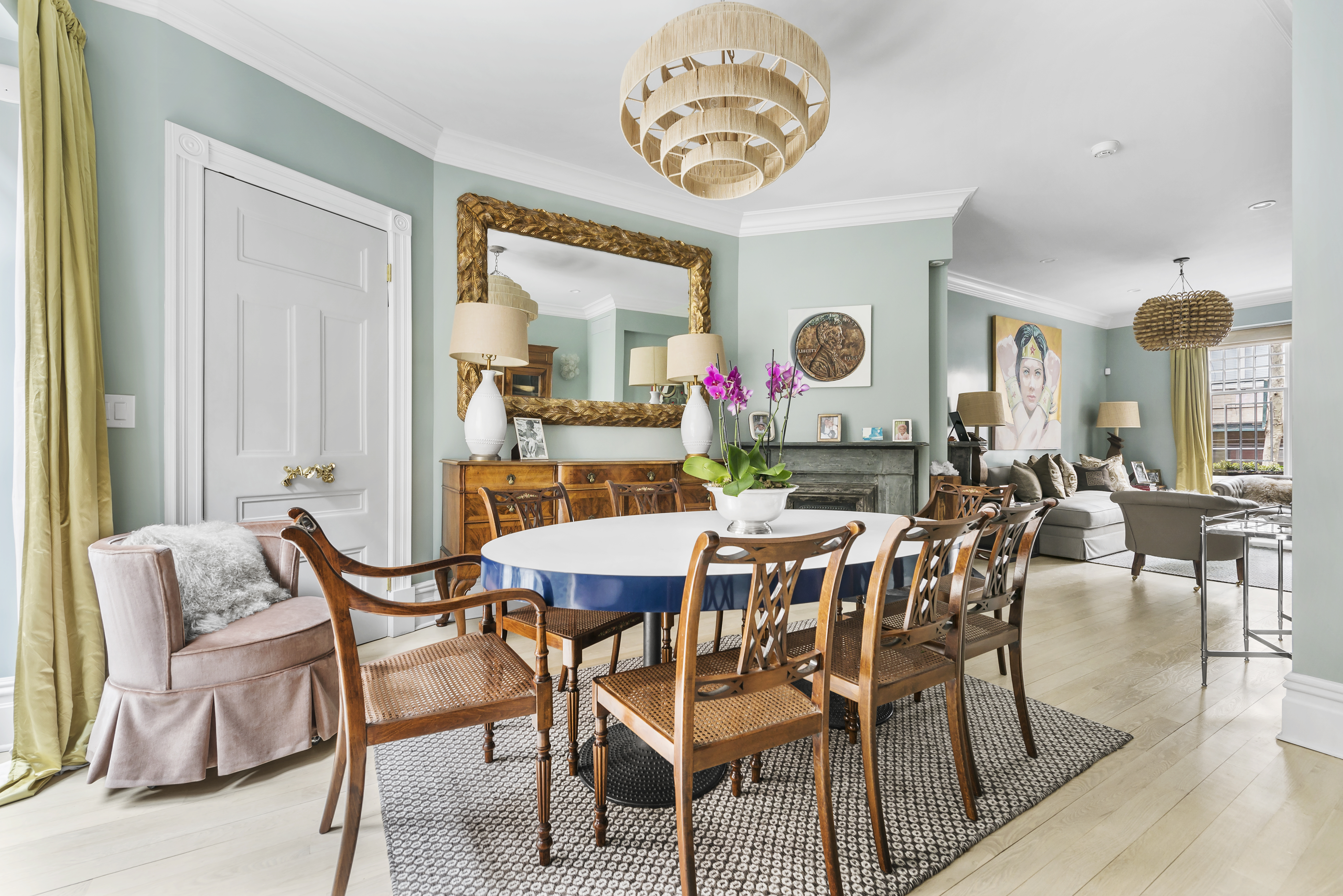 A dining area with a round table, light blue walls, crown moldings, and hardwood floors.
