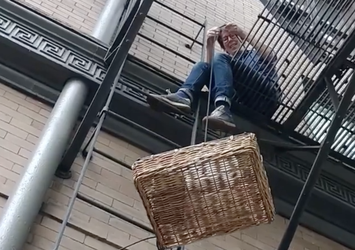 The Tin Table’s Hallie Kuperman lowers food down from a fire escape in a basket.
