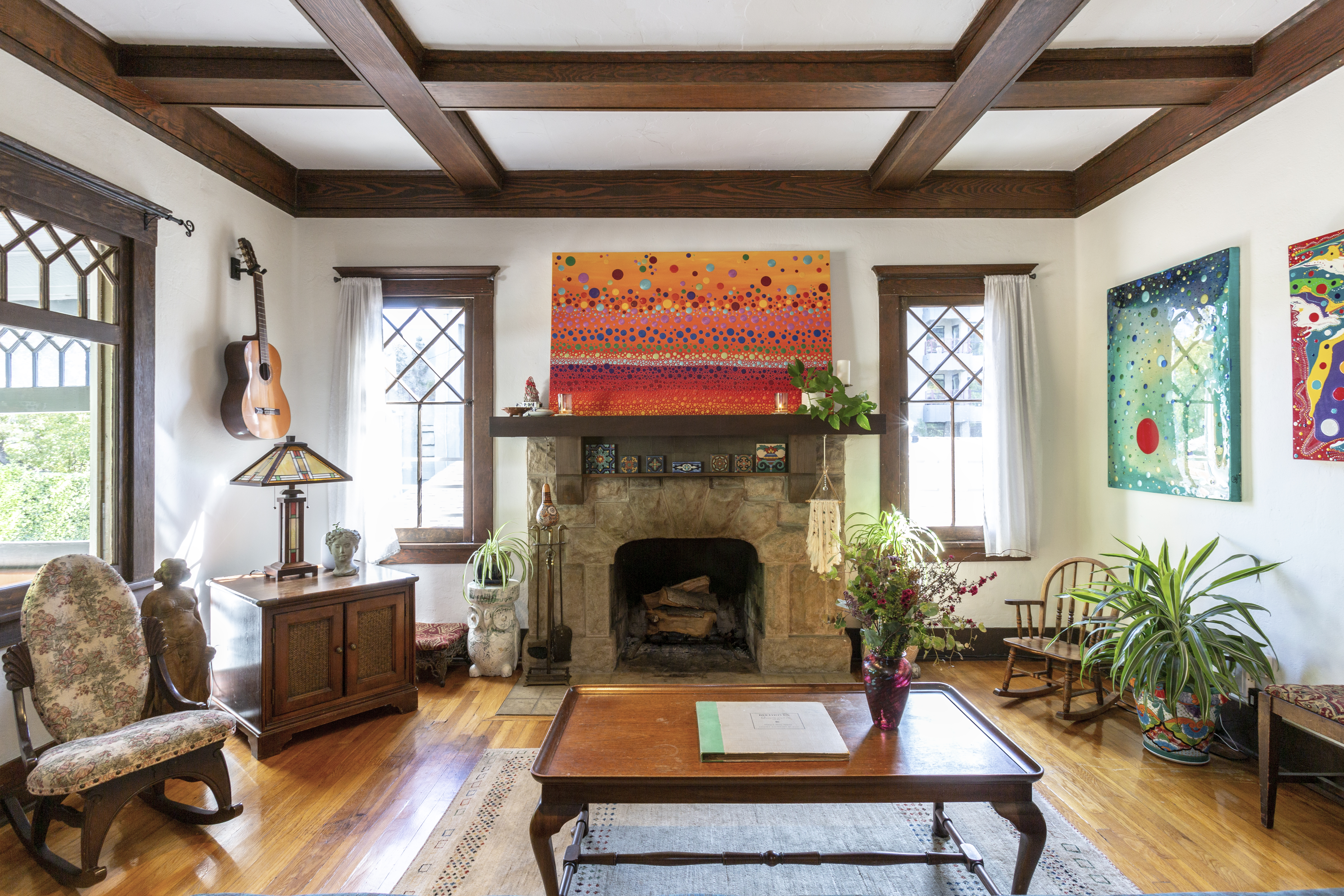 Room features stone fireplace, wooden floors, and art on walls.