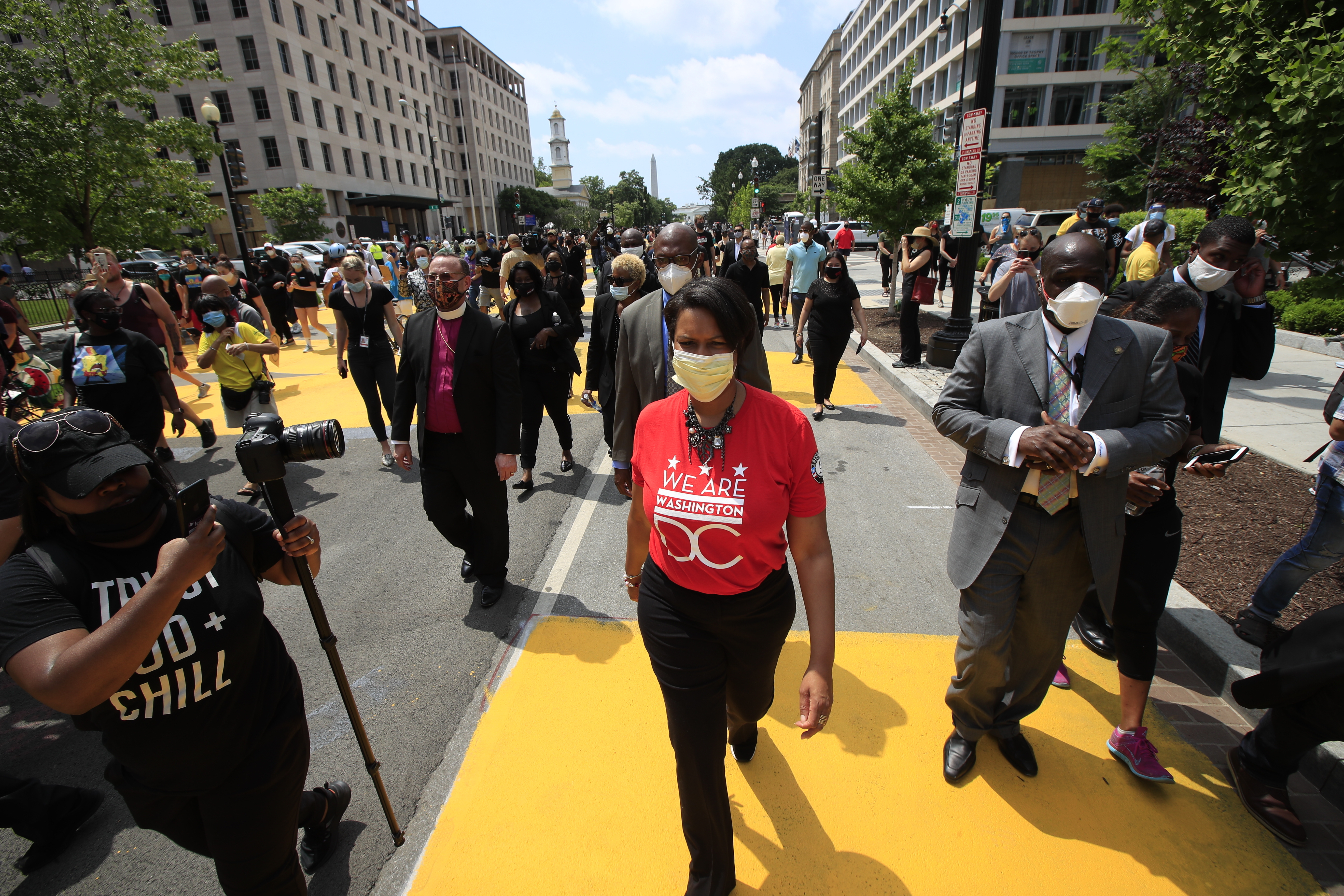哥伦比亚特区市长穆里尔·鲍泽(Muriel Bowser)走在通往白宫的街道上。此前，该市工作人员和活动人士在街道上用巨大的亮黄色字体写下了“黑人的命也是命”的字样。