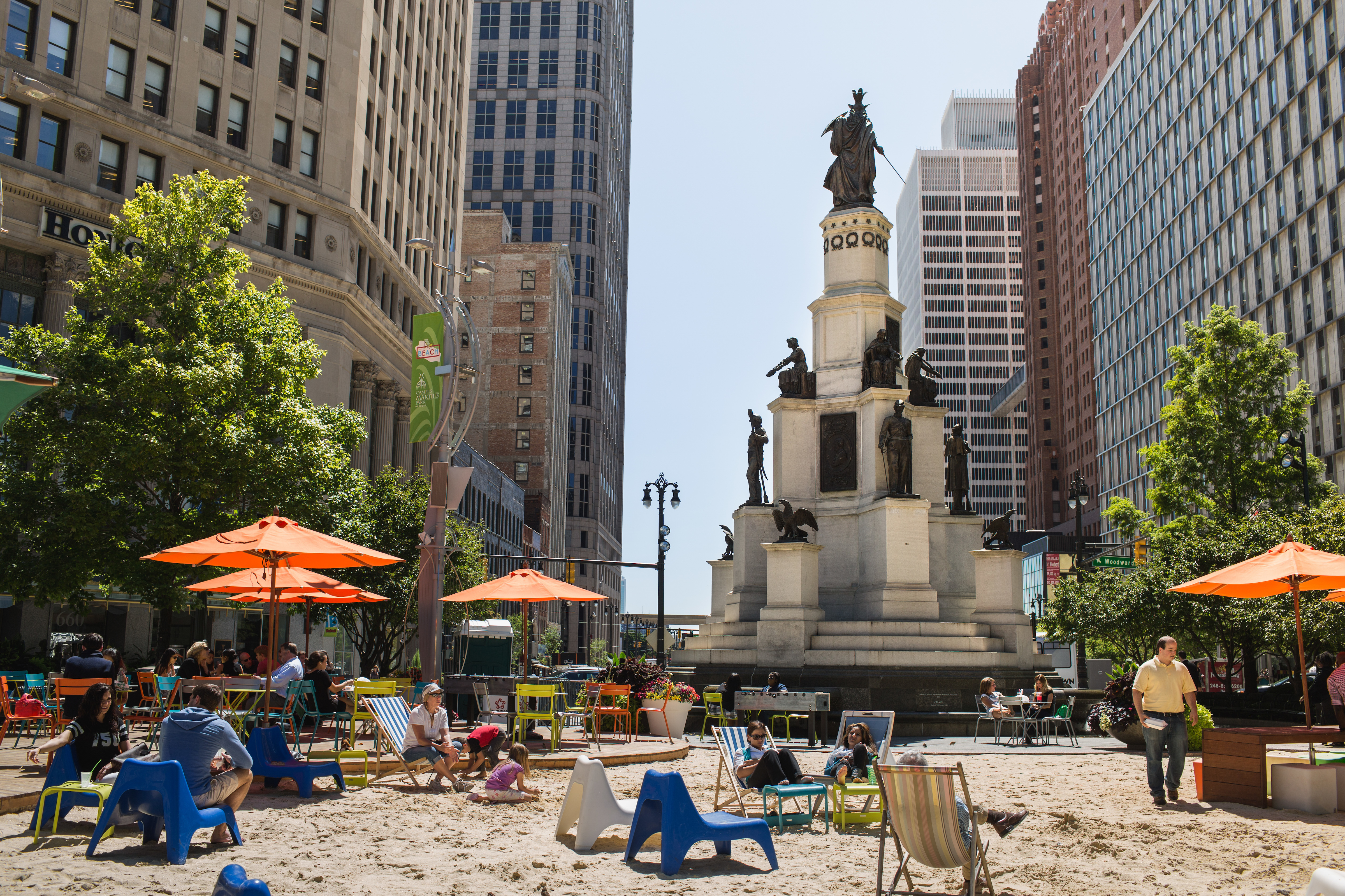 The beach at Campus Martius is filled with colored umbrellas and plastic chairs.