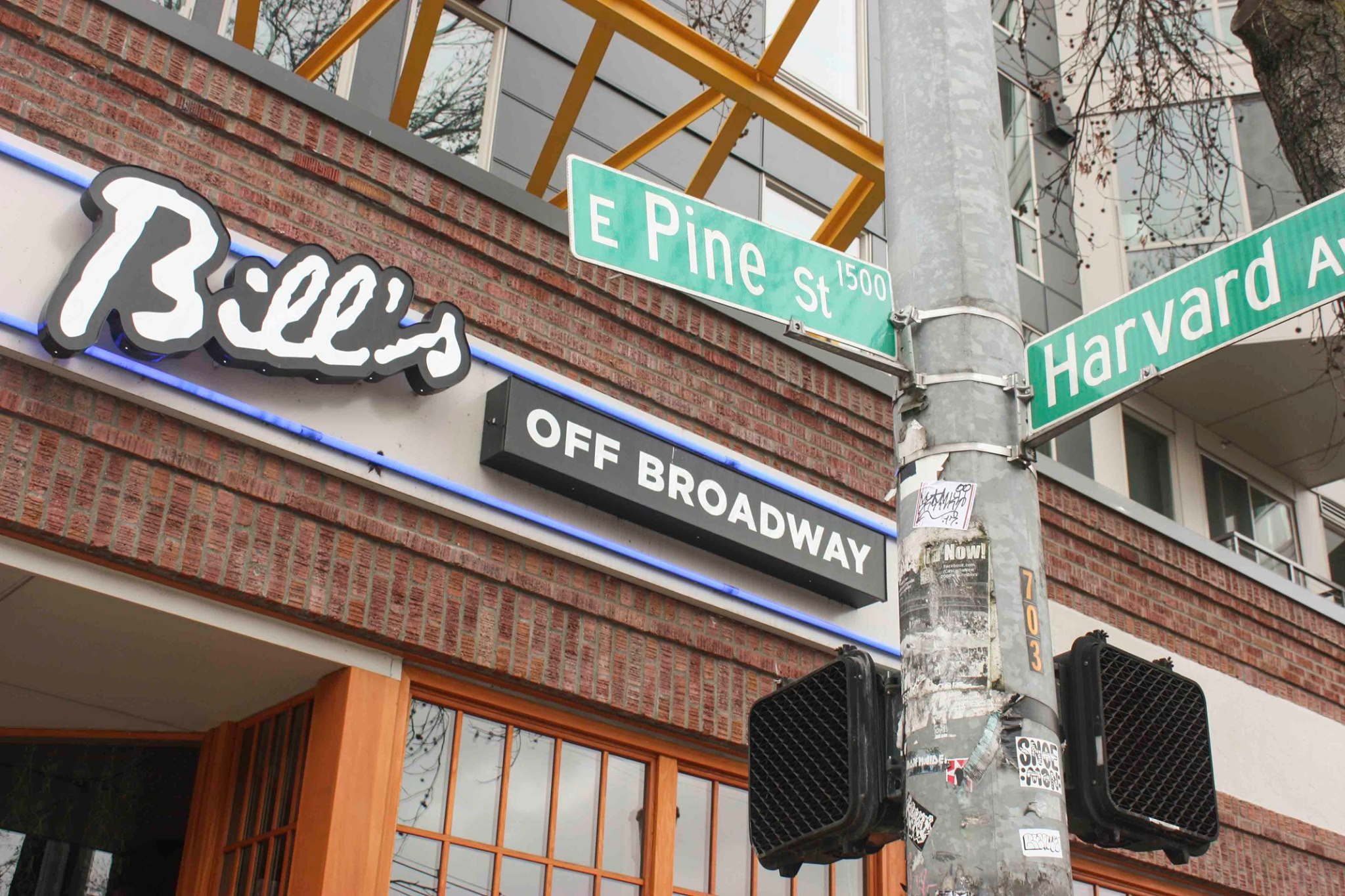 The front of Bill’s Off Broadway, with the street signs Pine Street and Harvard Avenue in the foreground