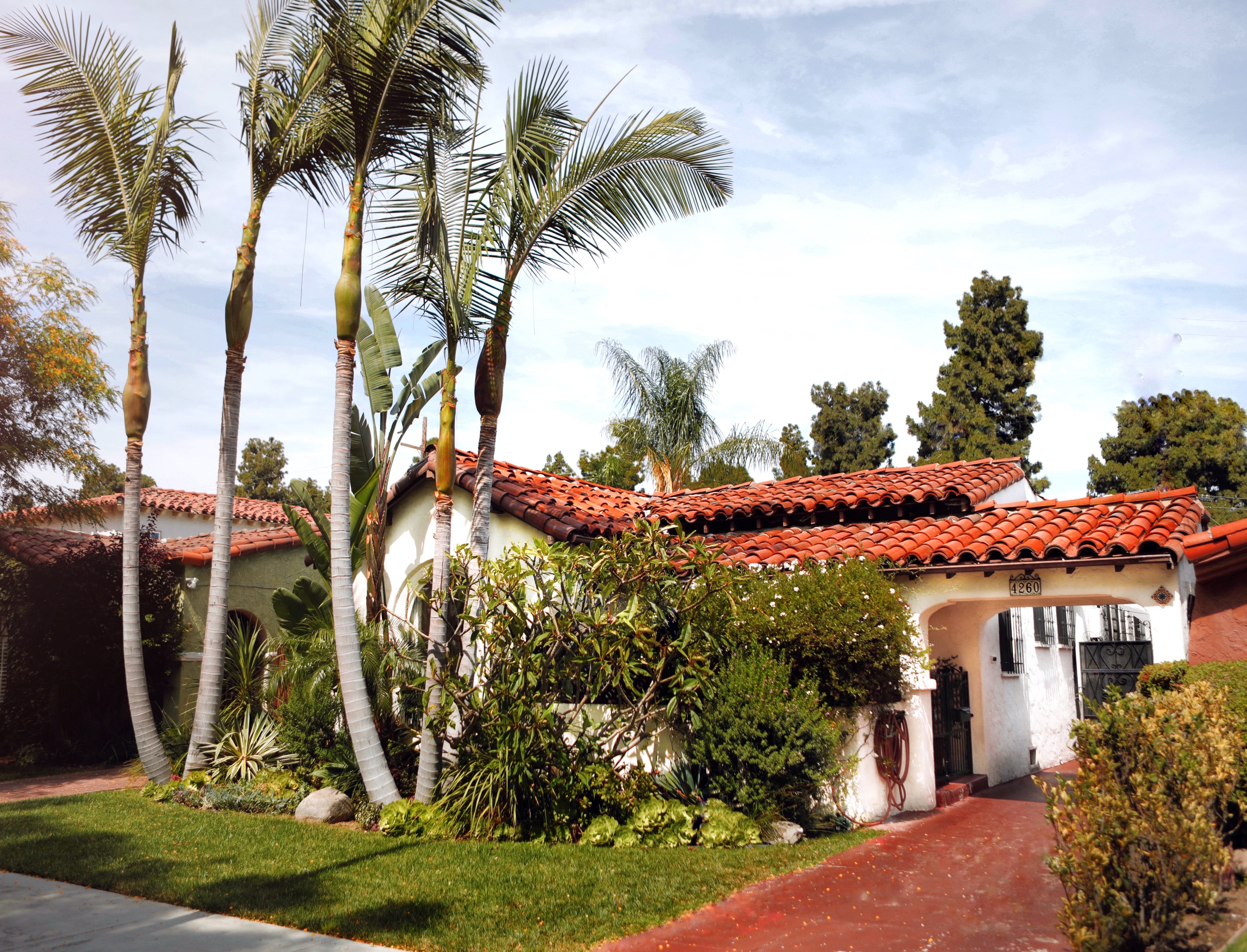 Tile-roofed home surrounded by palm trees.