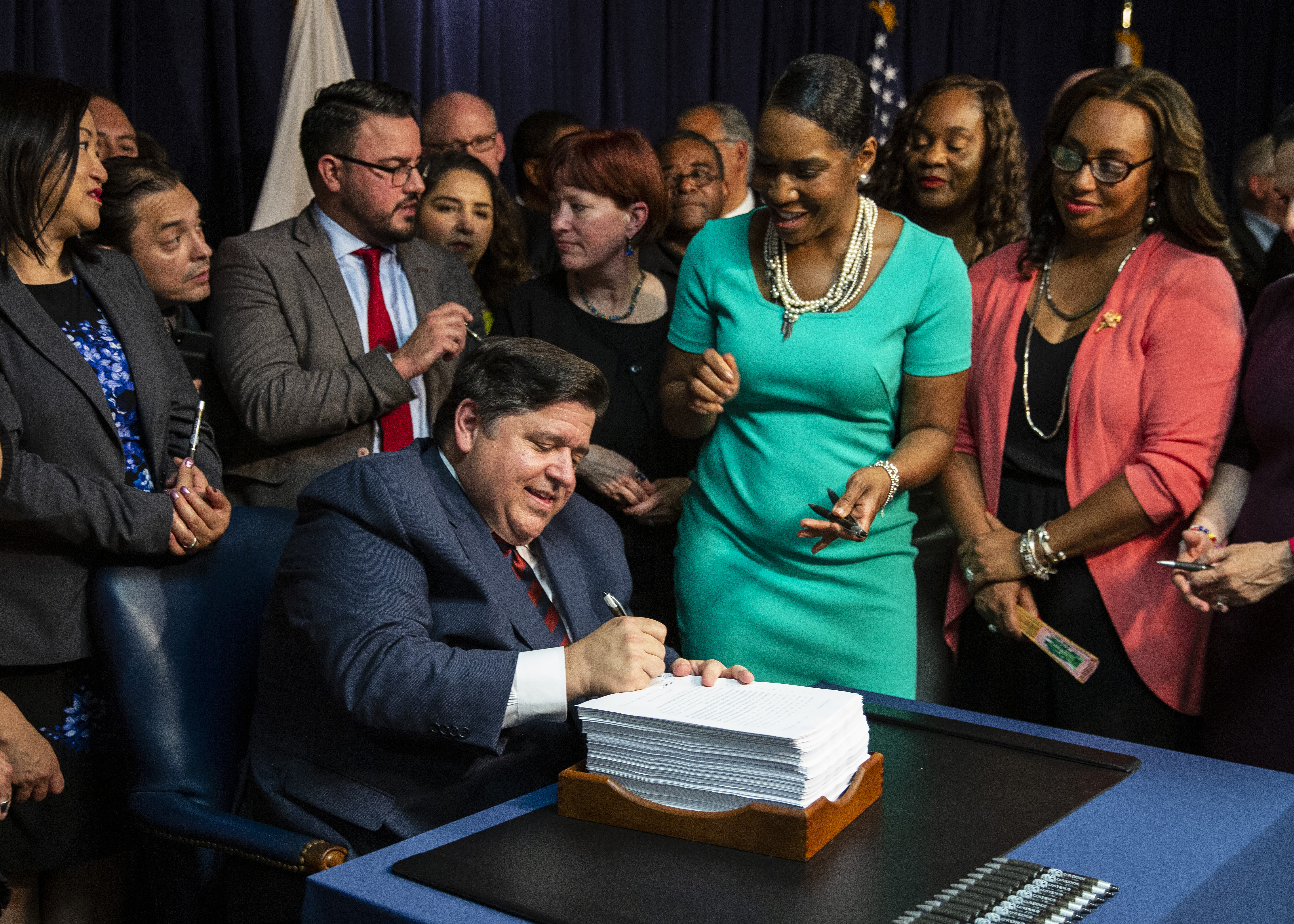 Flanked by supporters, Gov. J.B. Pritzker signs revenue and budget legislation at the James R. Thompson Center last  year.