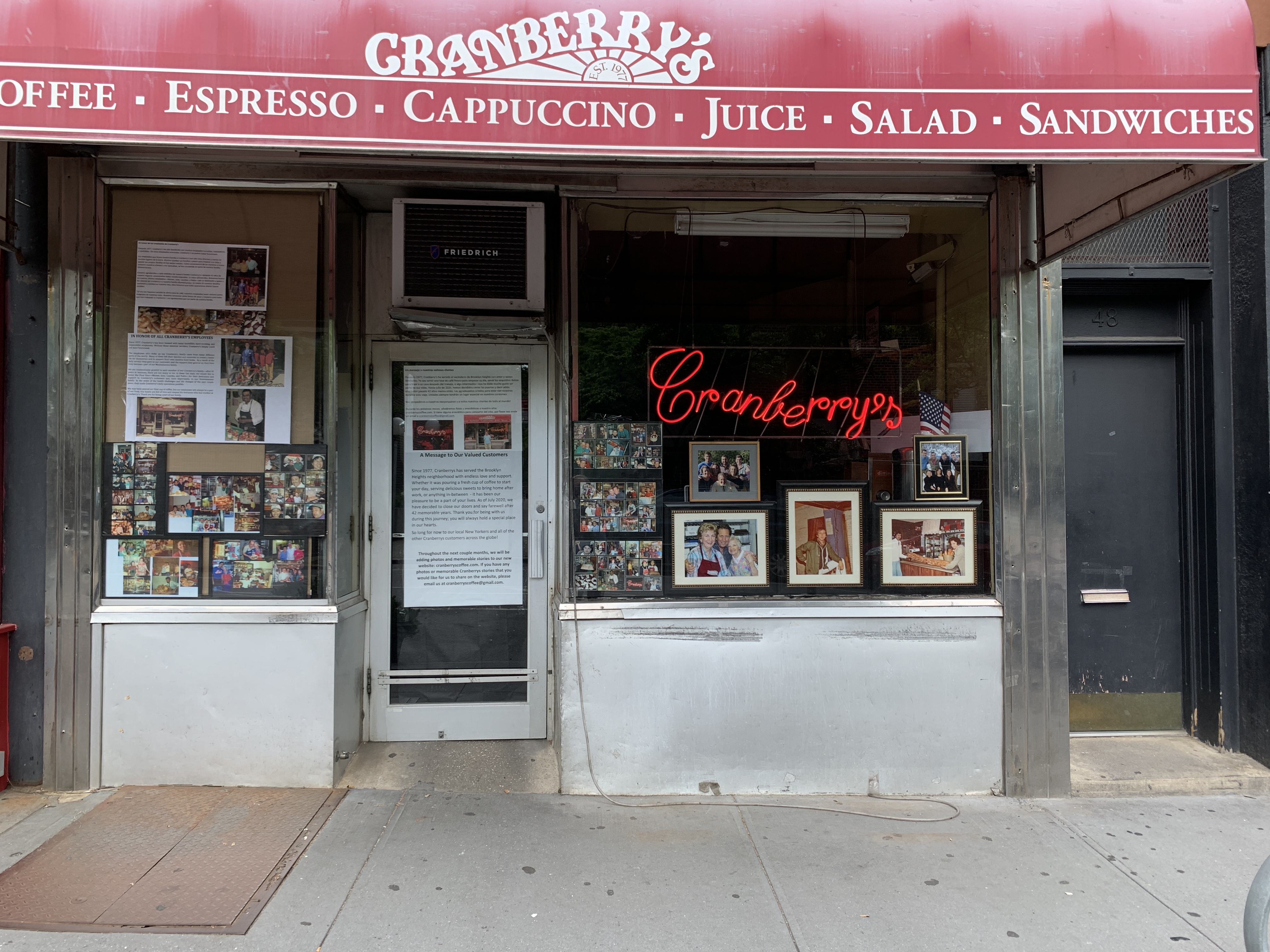 The exterior of a shop with a red awning, and a neon red sign that reads cranberry’s