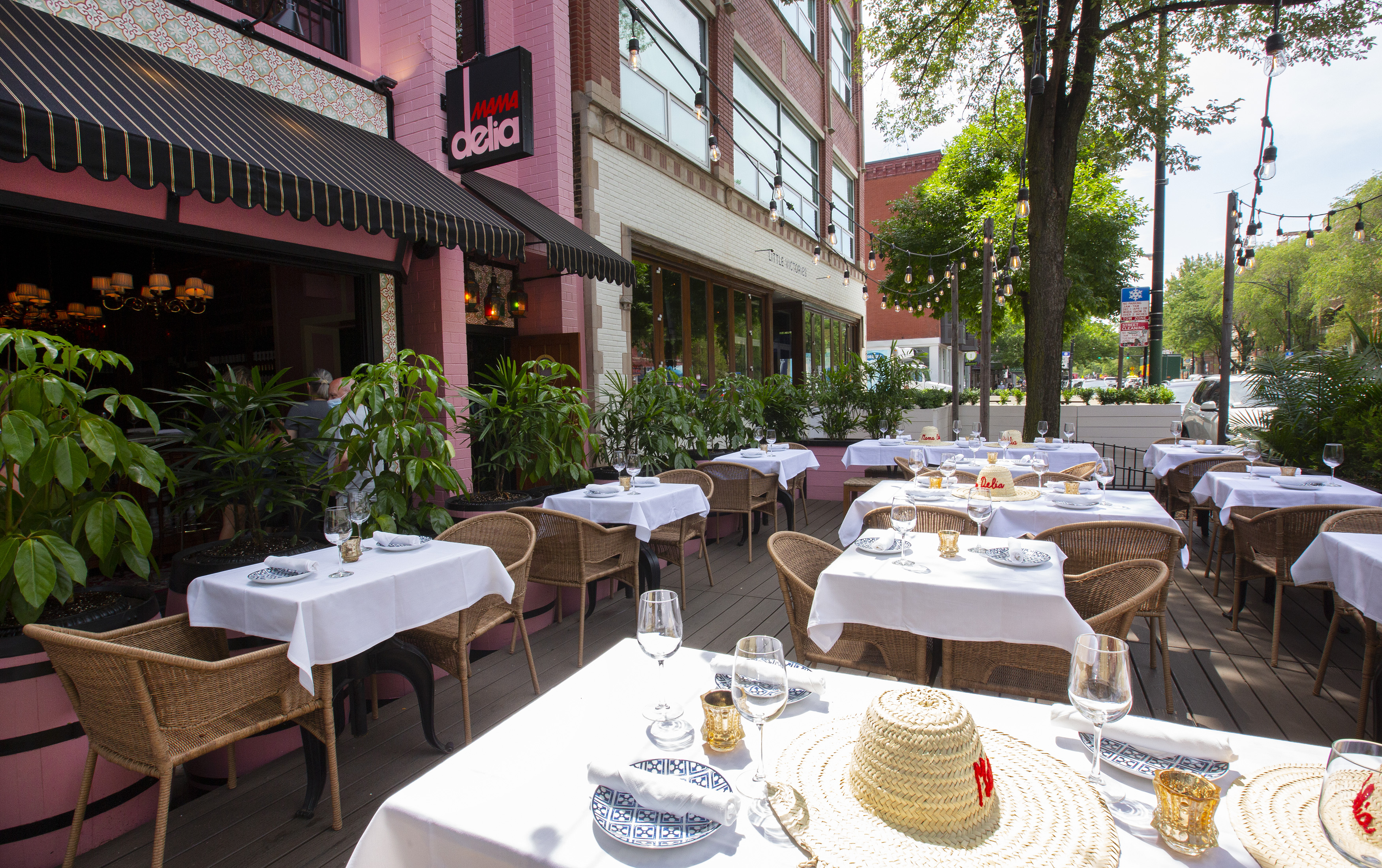 A large outdoor patio for dining next to a pink building.