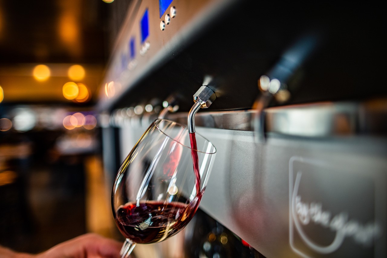 A tap pouring wine into a glass at self-pour bar Rapport