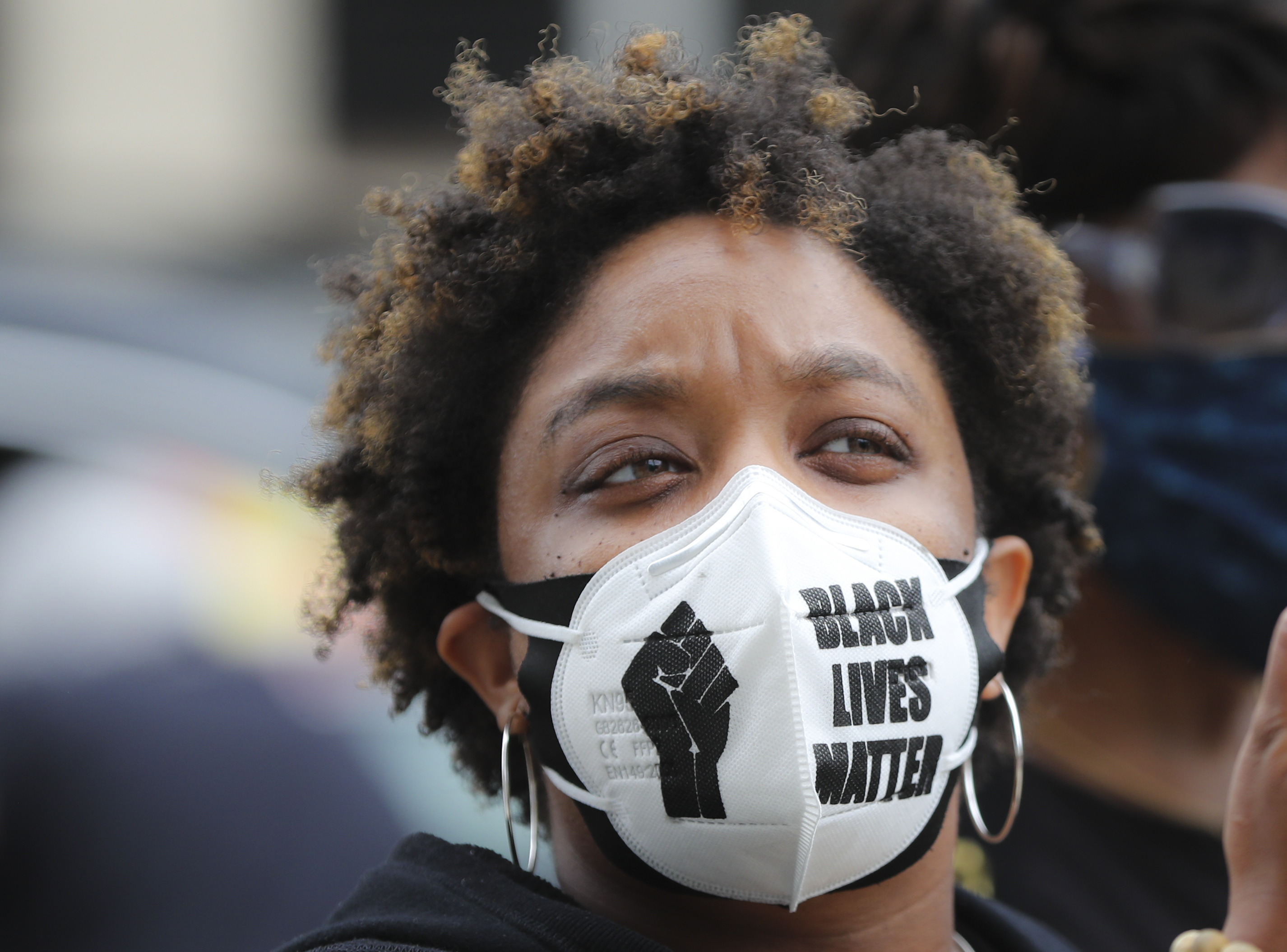 A Black person wearing a face mask that reads “Black lives matter.”