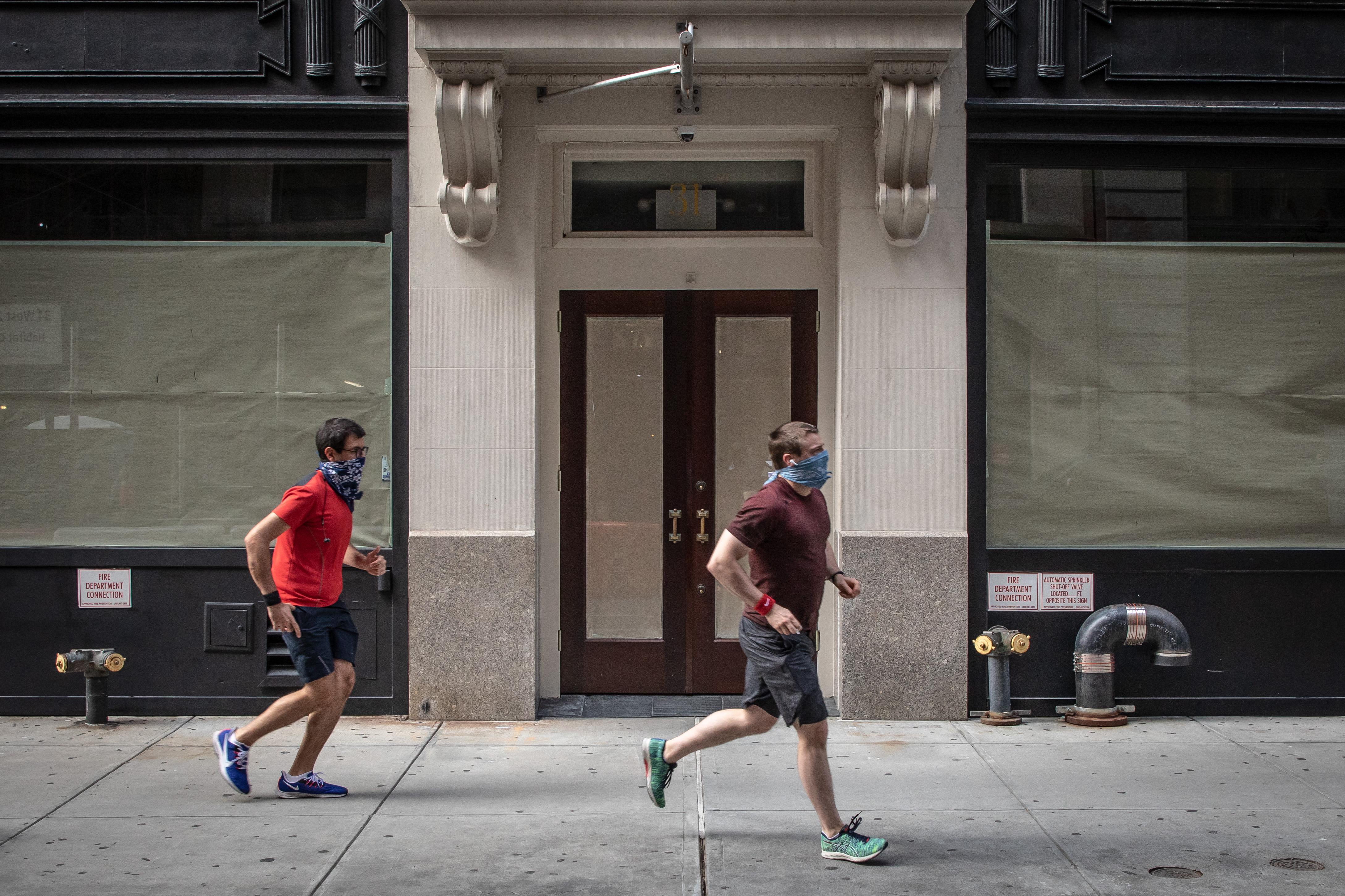 Two runners can be seen outside a storefront that has been covered up from the inside