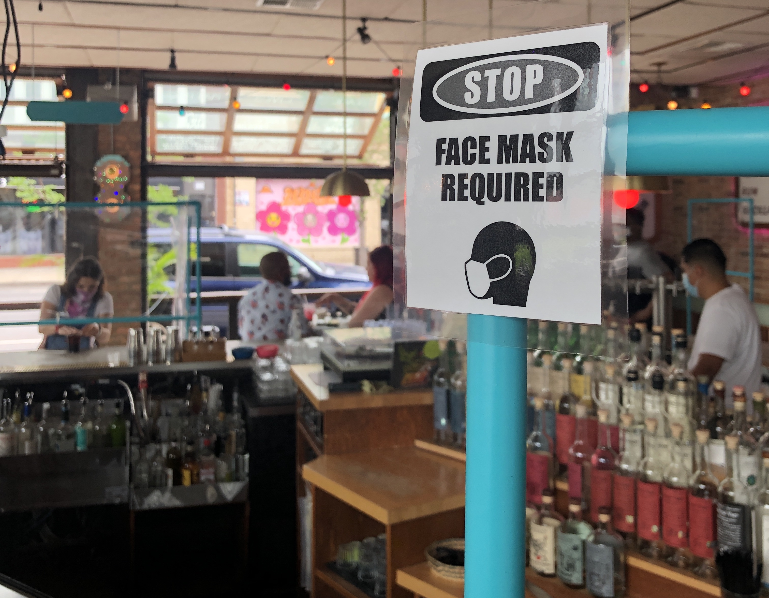 A bar with a “face mask required” sign on its counter.