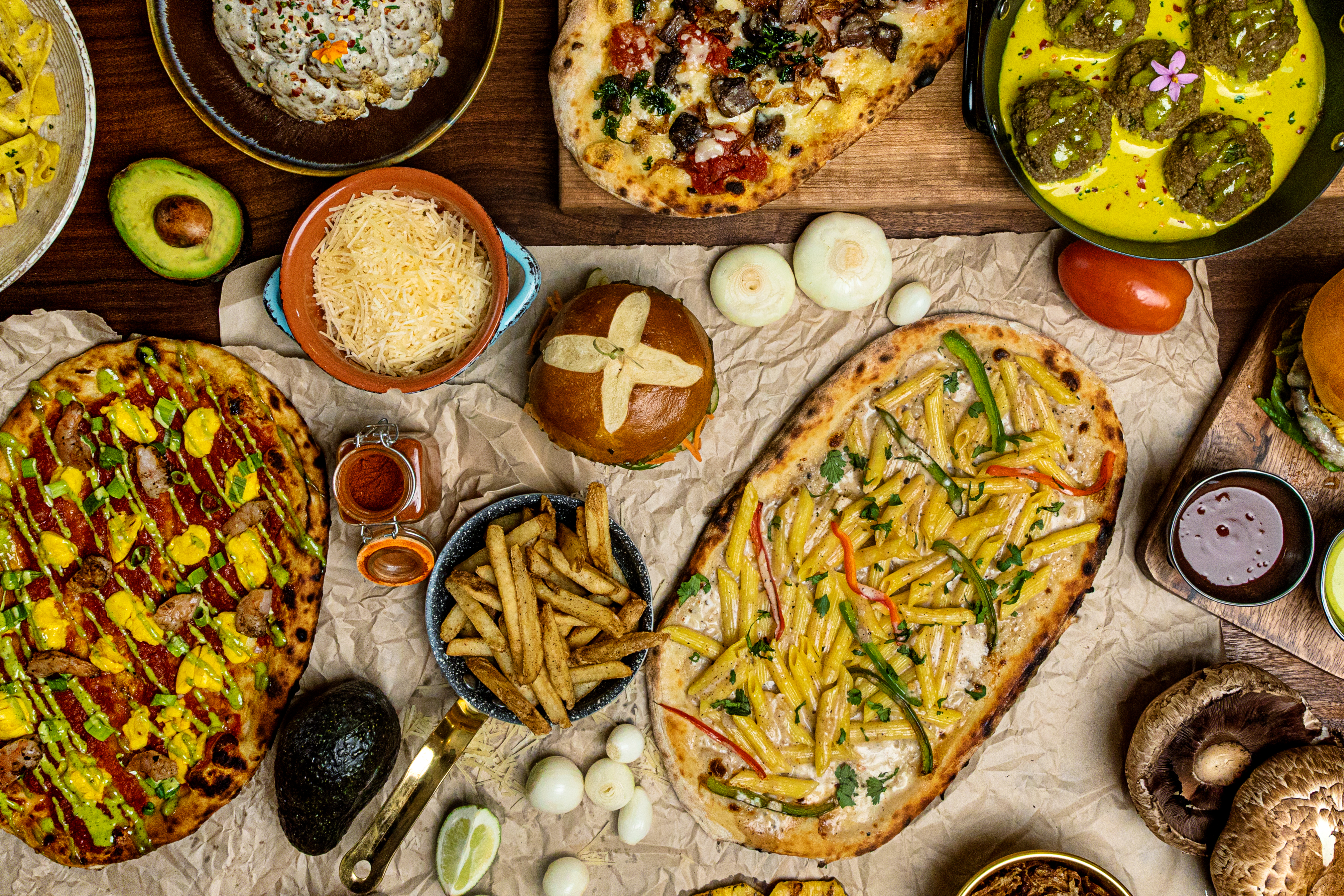 Flatbread pizzas, pretzel buns, mushrooms, and more menu items spread out on a table