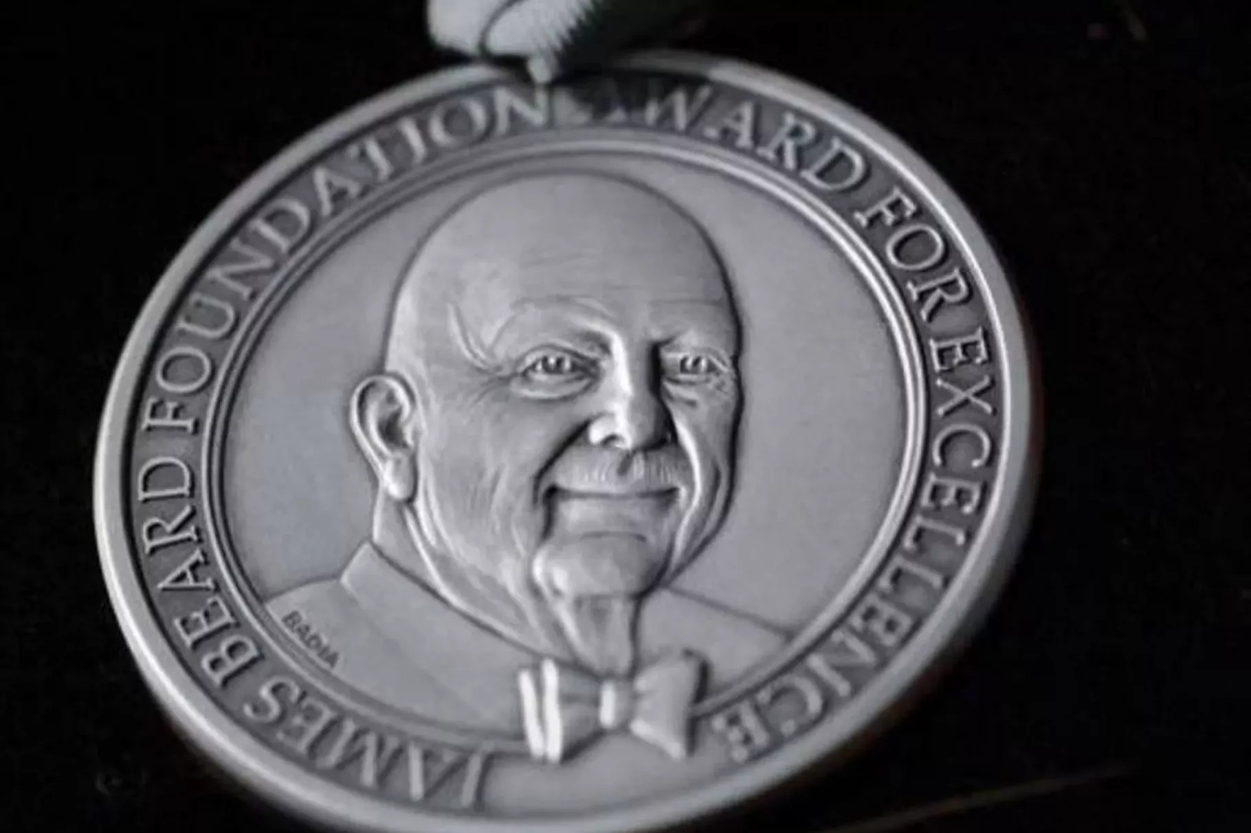 A silver James Beard Awards medal on a black background.