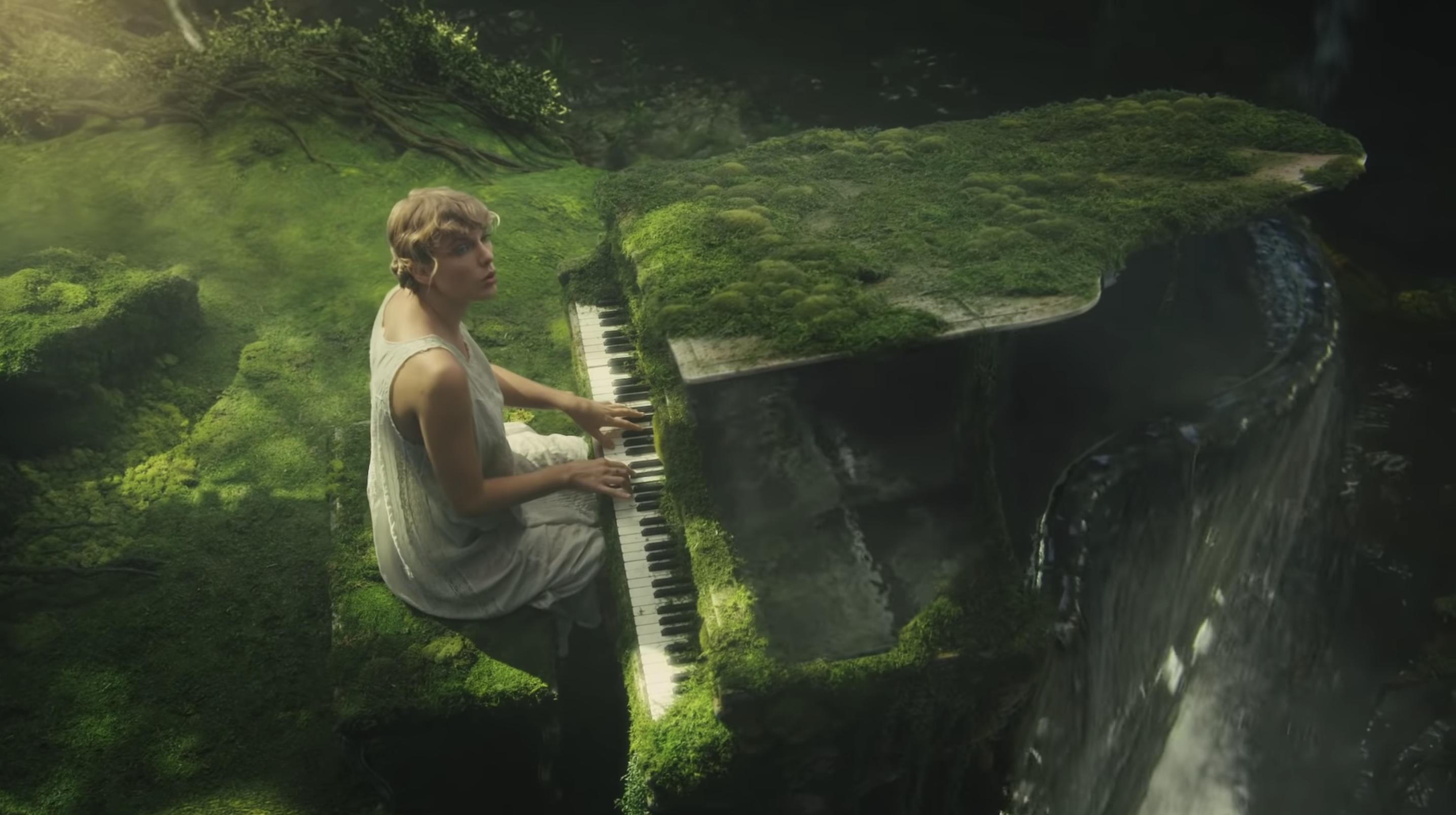 Taylor Swift sits at her piano in a forest in the music video for “Cardigan.”