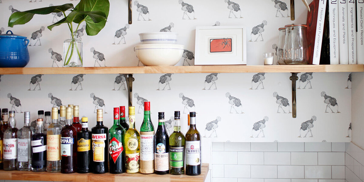 The bar at Homer, with some cookbooks lined up on a shelf, and light-colored wallpaper displaying birds