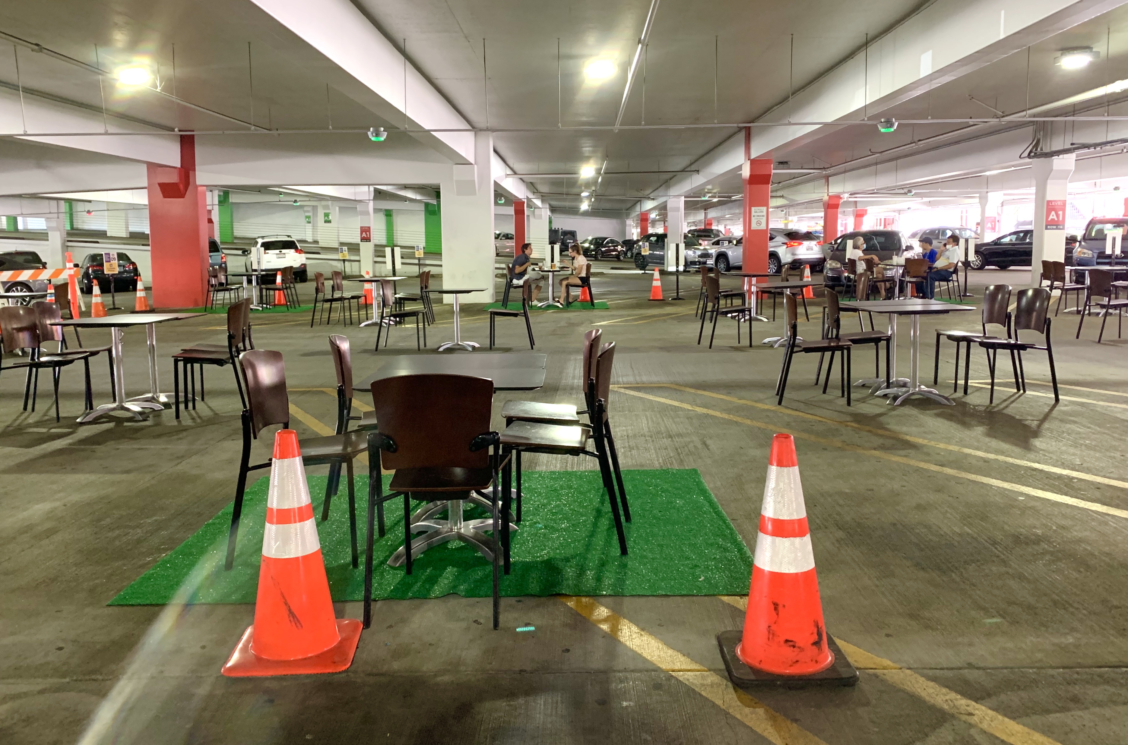 A table set up in a parking garage is surrounded by cones and astroturf as part of an outdoor dining program at Glendale Galleria in Los Angeles. 
