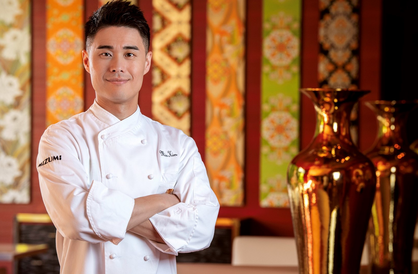 A chef stands with his arms crossed
